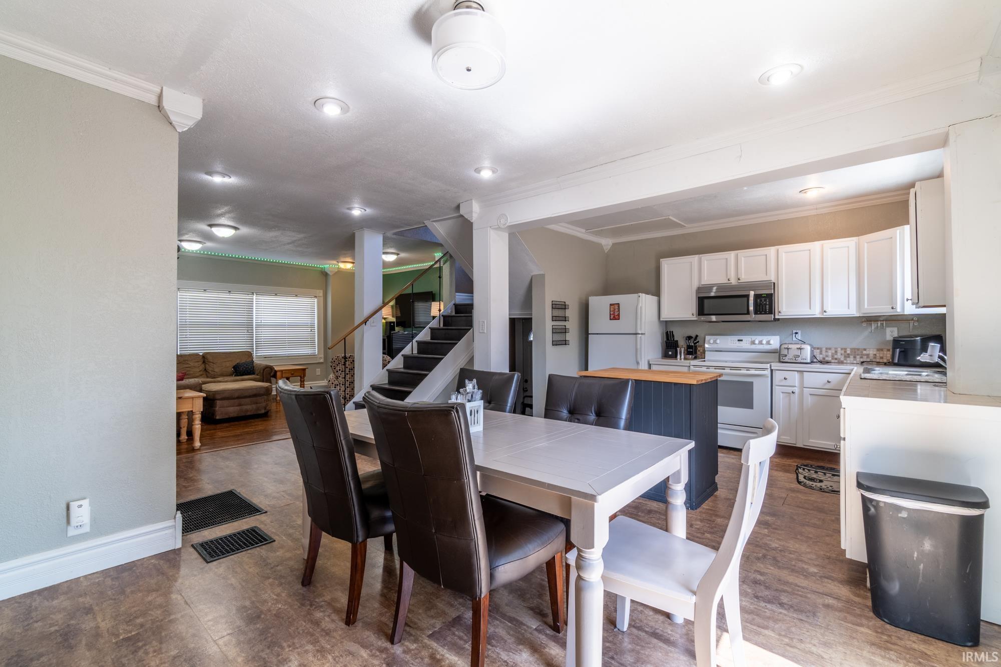 Open-concept living space featuring wood-finish flooring, recessed lighting, and crown molding