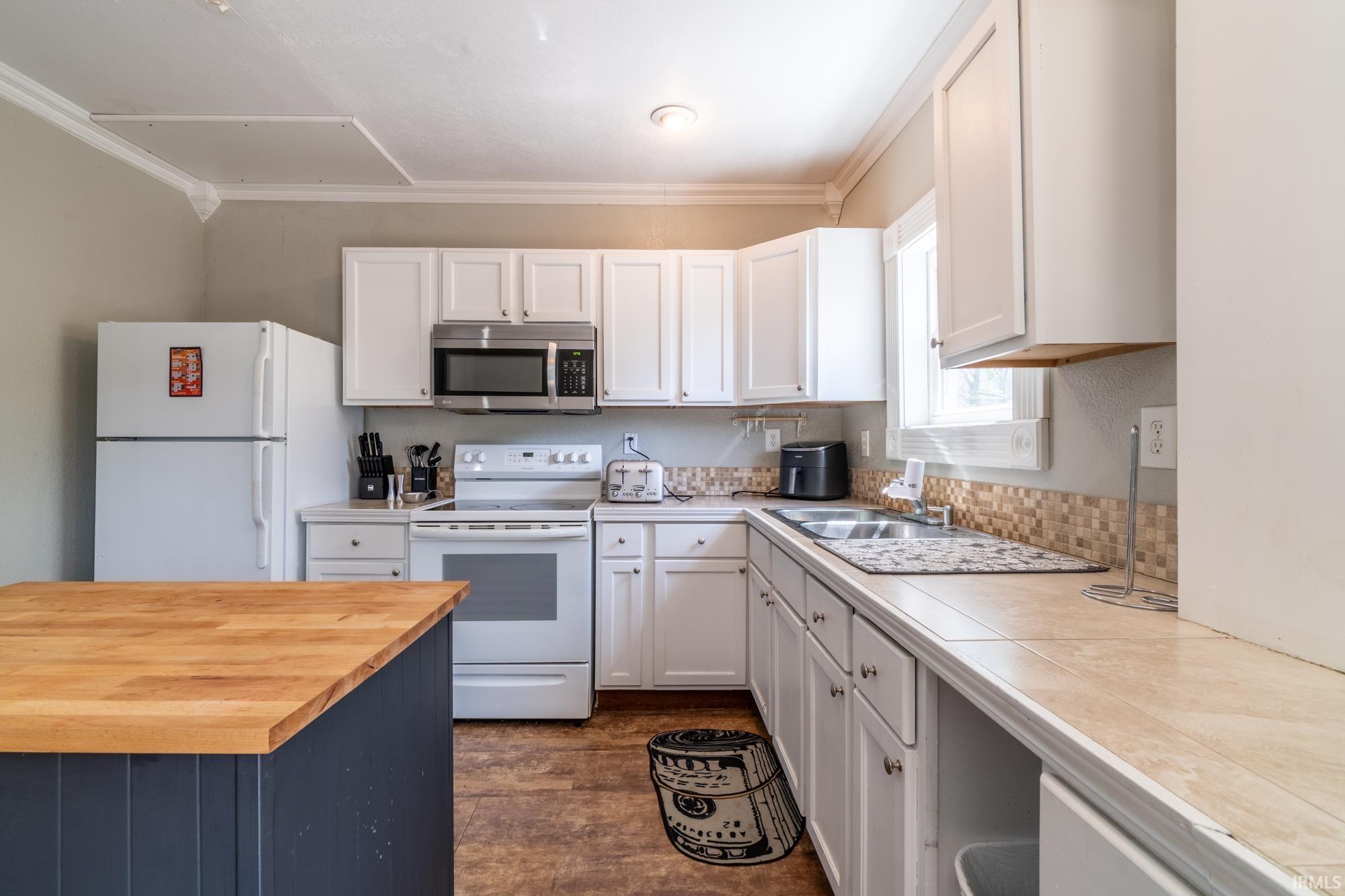 Kitchen featuring white cabinetry, stainless steel microwave, white electric range, and wood-finish flooring