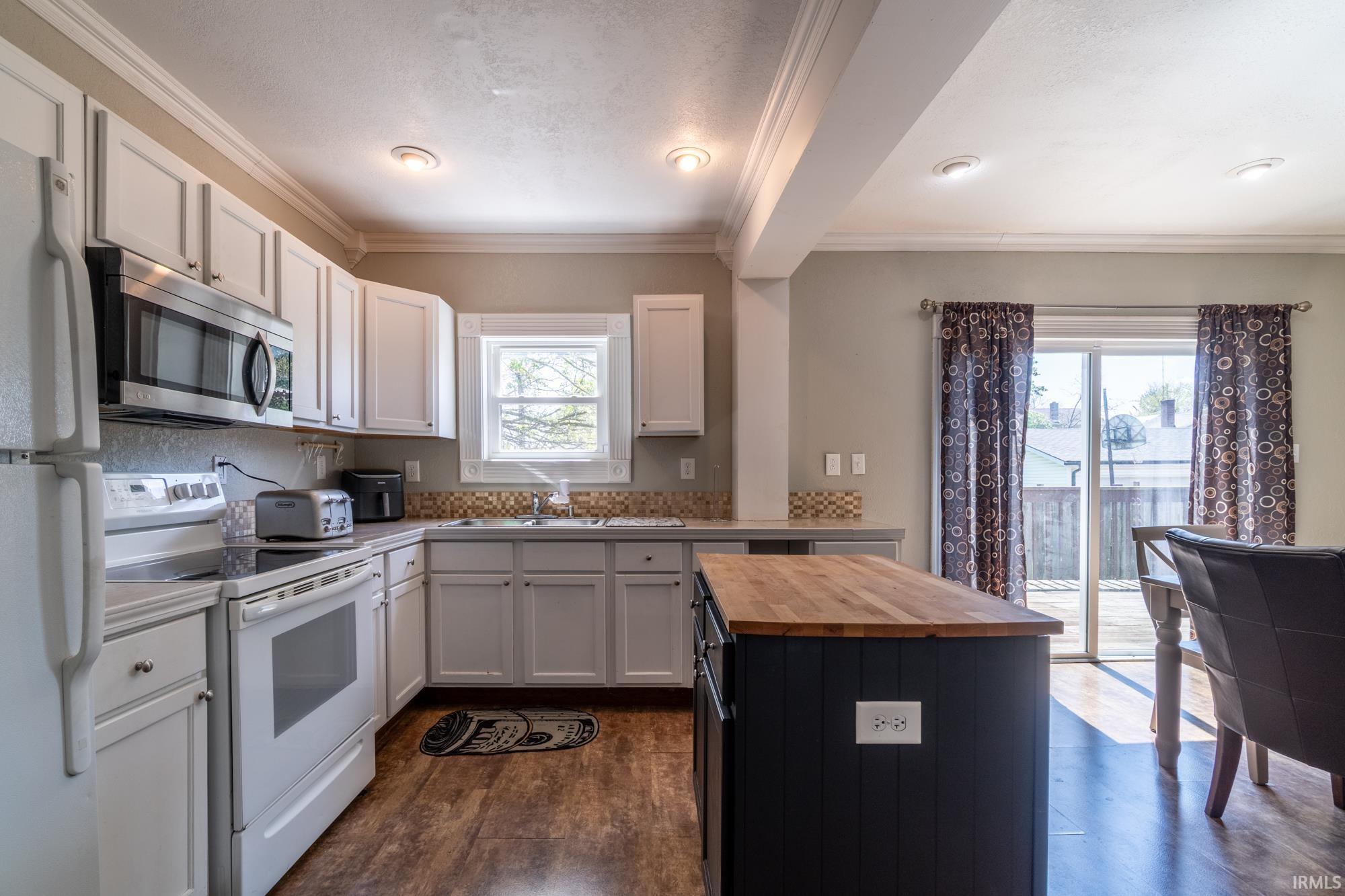 Kitchen featuring white cabinetry, stainless steel appliances, a tile backsplash, and wood-finish flooring