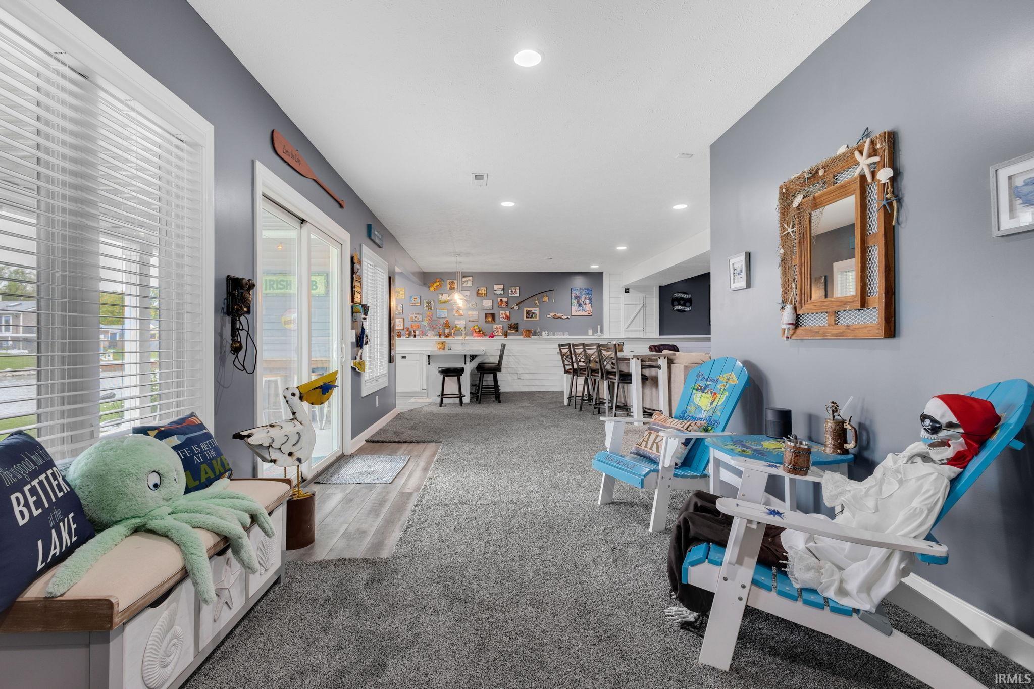 Spacious recreational area featuring recessed lighting, a sliding glass door, and a built-in bar with seating for four