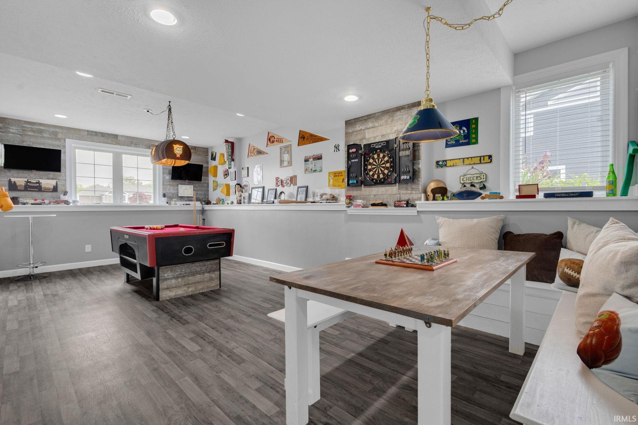 Recreation room featuring wood-finish flooring, two large windows, recessed lighting, and a built-in bench seating area