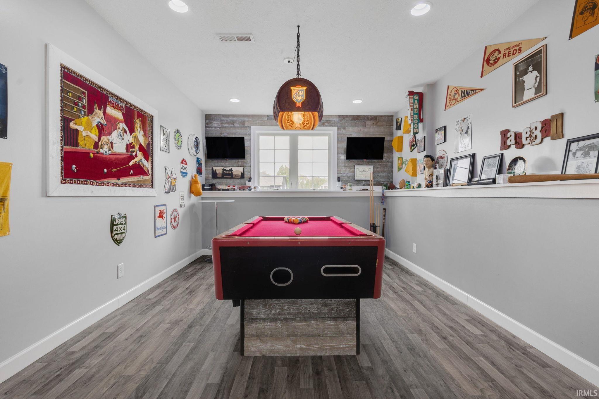 Recreation space featuring a billiard table with red felt, wood-finish flooring, and white baseboards