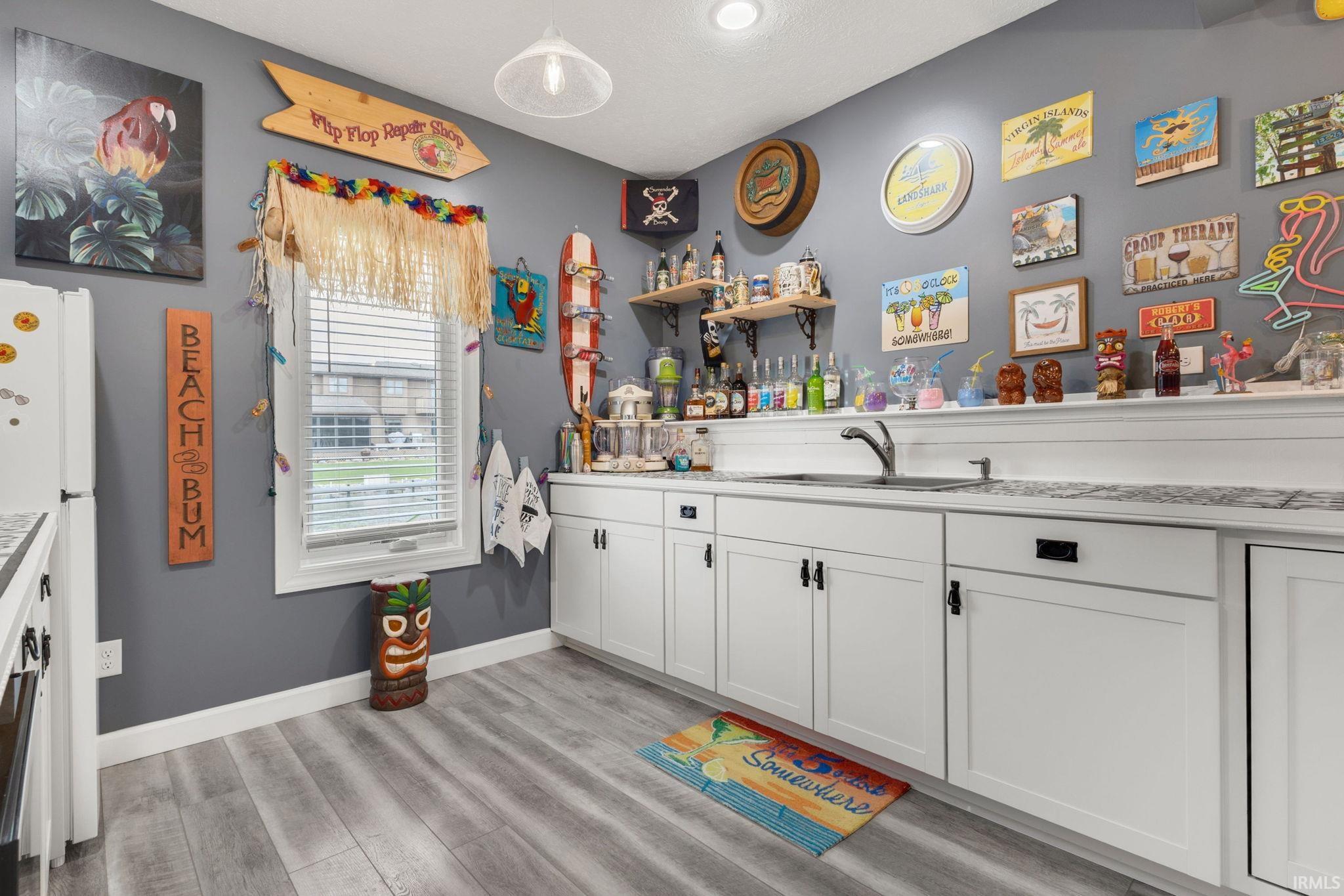 Contemporary kitchen featuring white shaker-style cabinetry, a stainless steel undermount sink, and light-toned wood-finish flooring