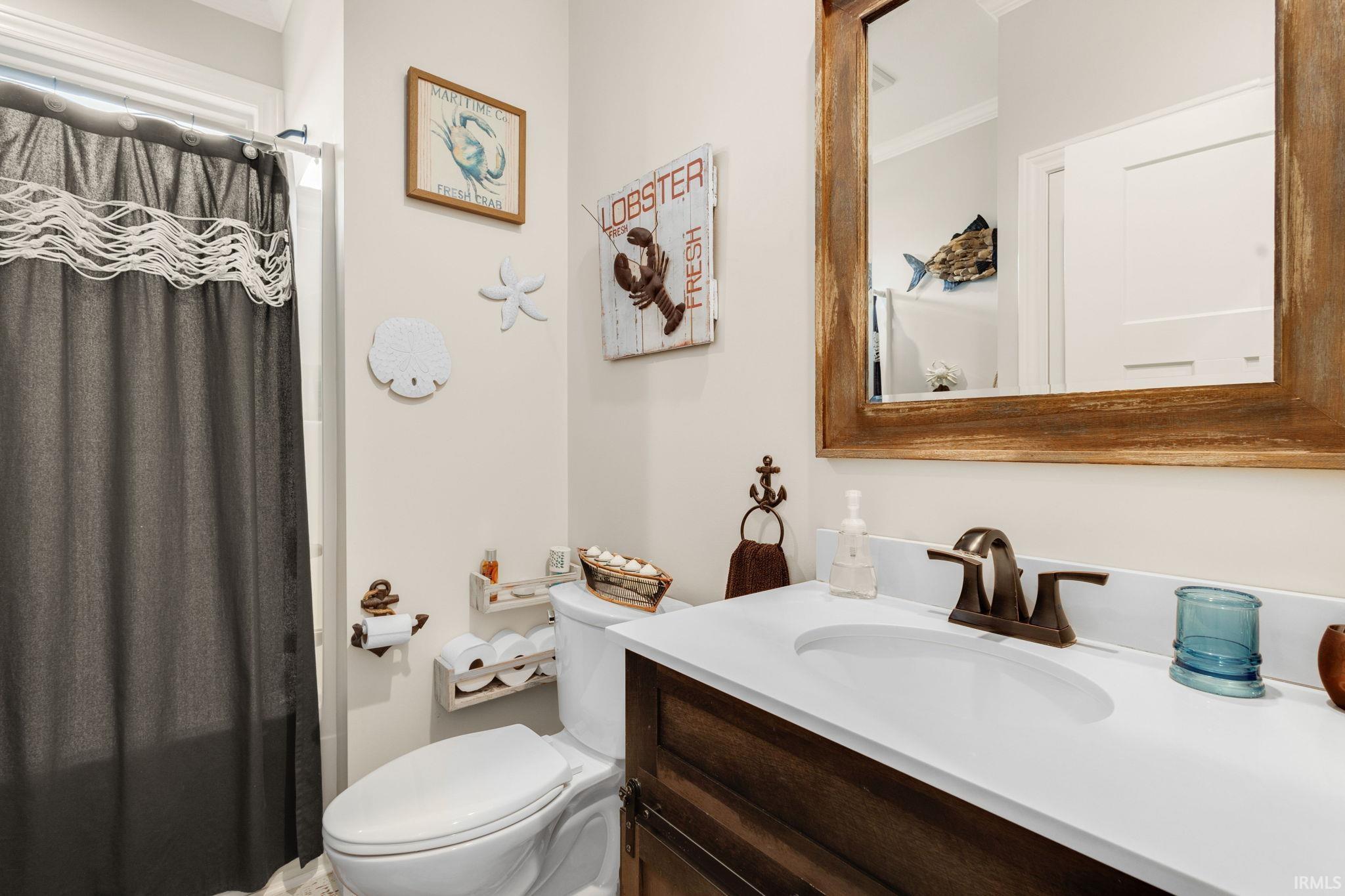 Bathroom featuring a white integrated sink with a bronze-finish faucet, a rectangular wood-frame mirror, and a dark wood-finish vanity
