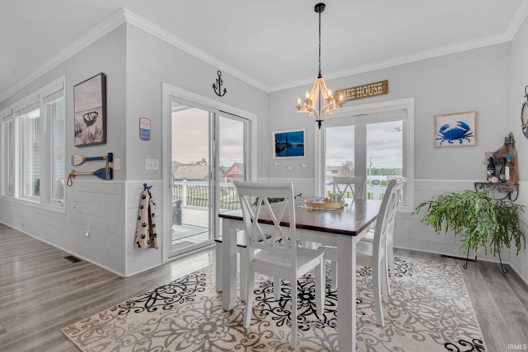 Dining area featuring a wood-finish flooring, white shiplap wainscoting, and large windows