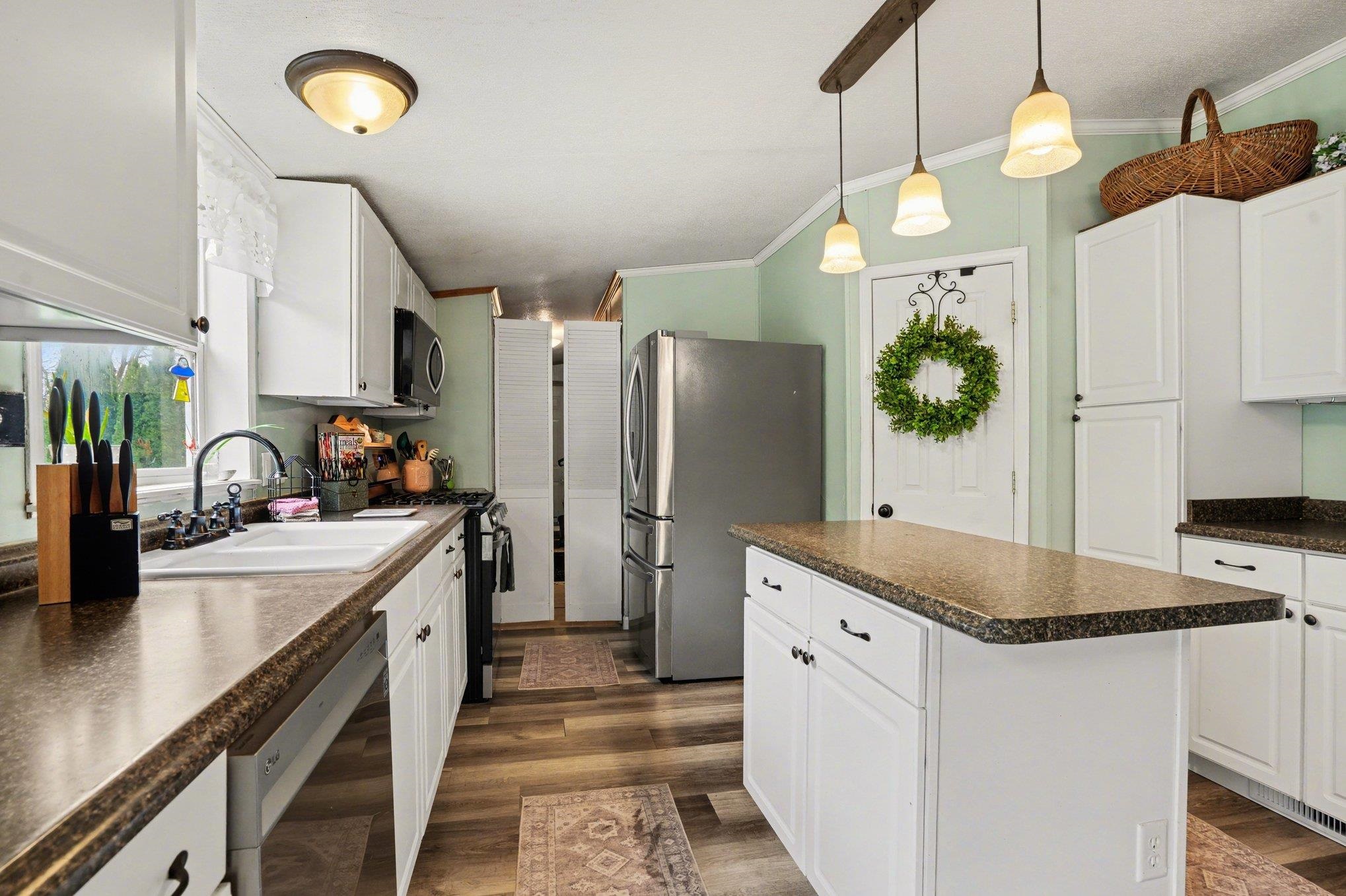 Kitchen featuring white cabinetry, wood-finish flooring, and a central island with a stone-finish countertop