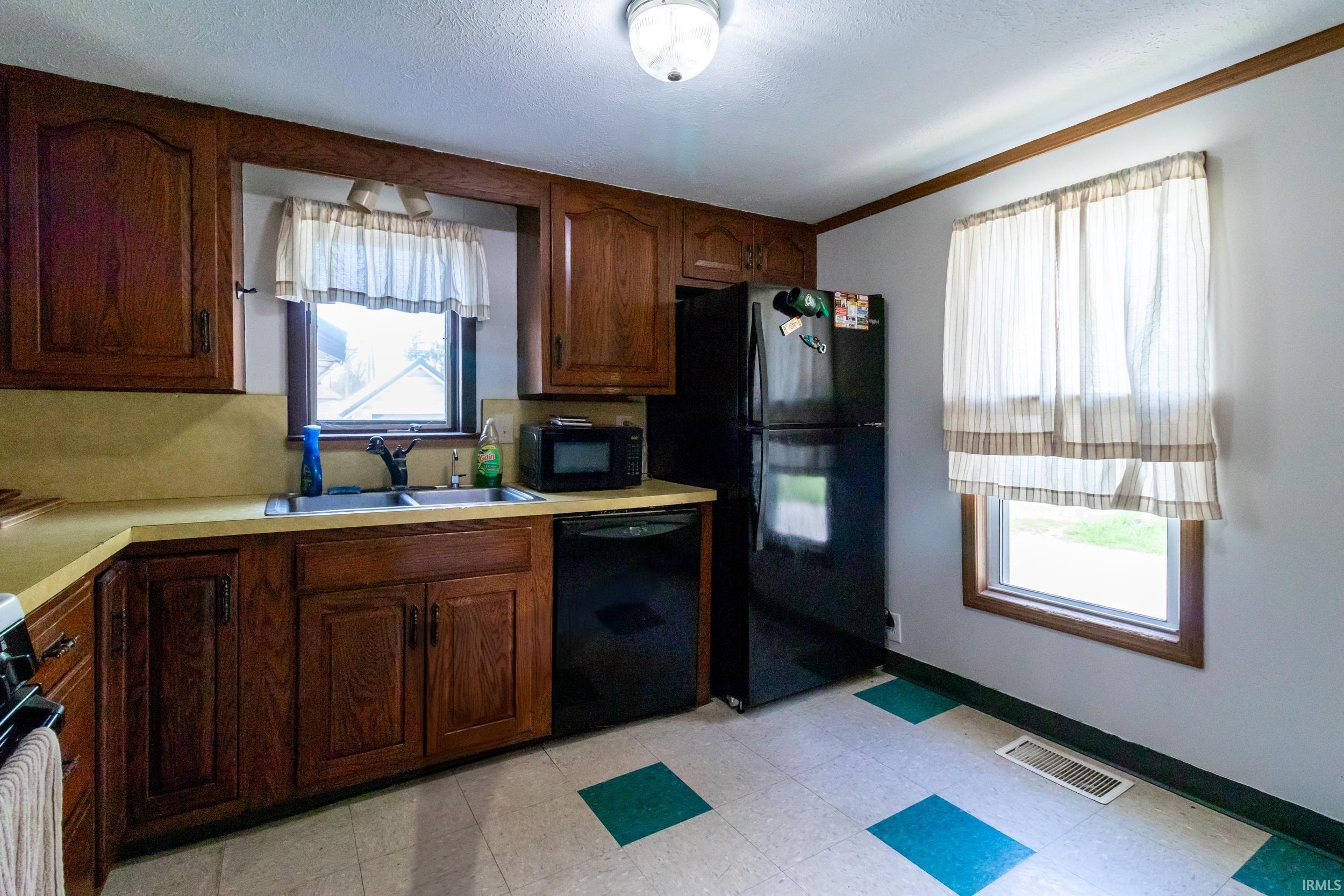 Kitchen featuring wood-finish cabinetry, a double basin sink with black faucet, and a black dishwasher