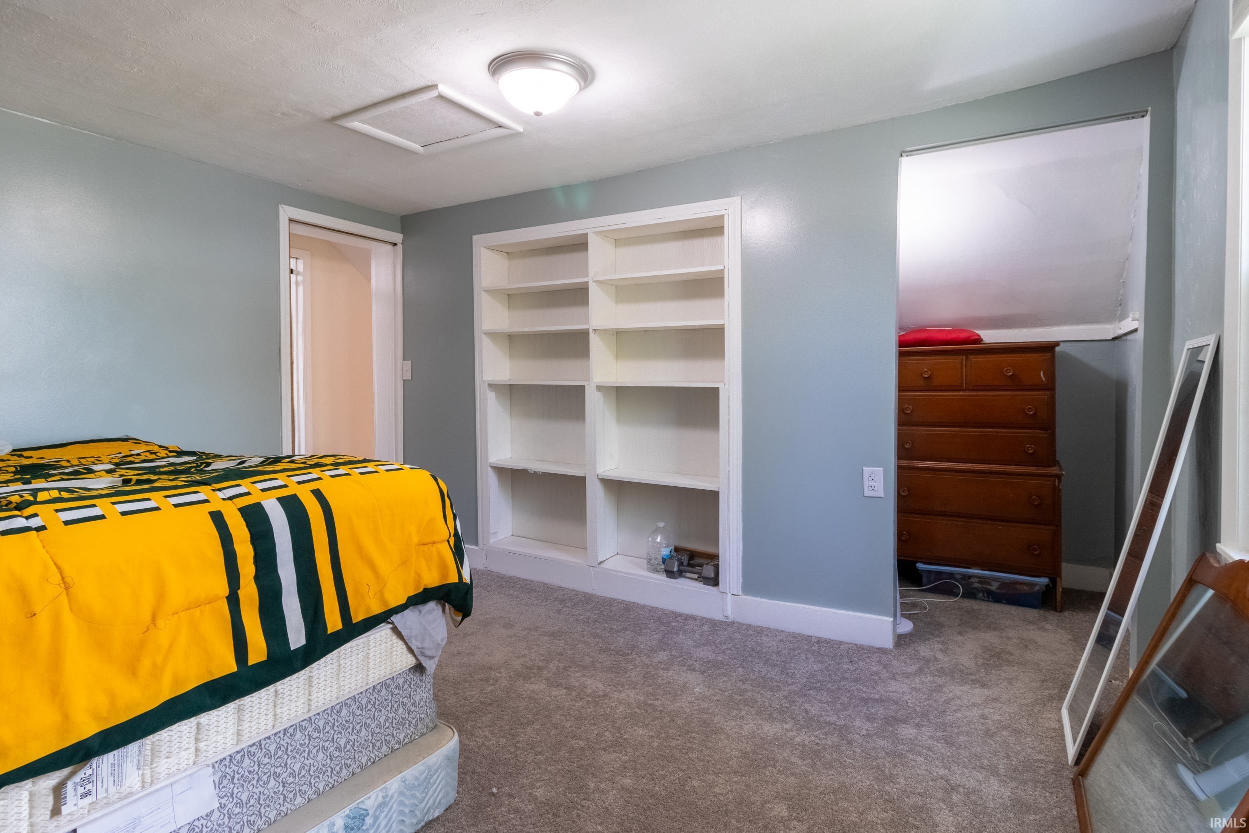 Carpeted room featuring light blue walls, a ceiling-mounted light fixture, and built-in shelving