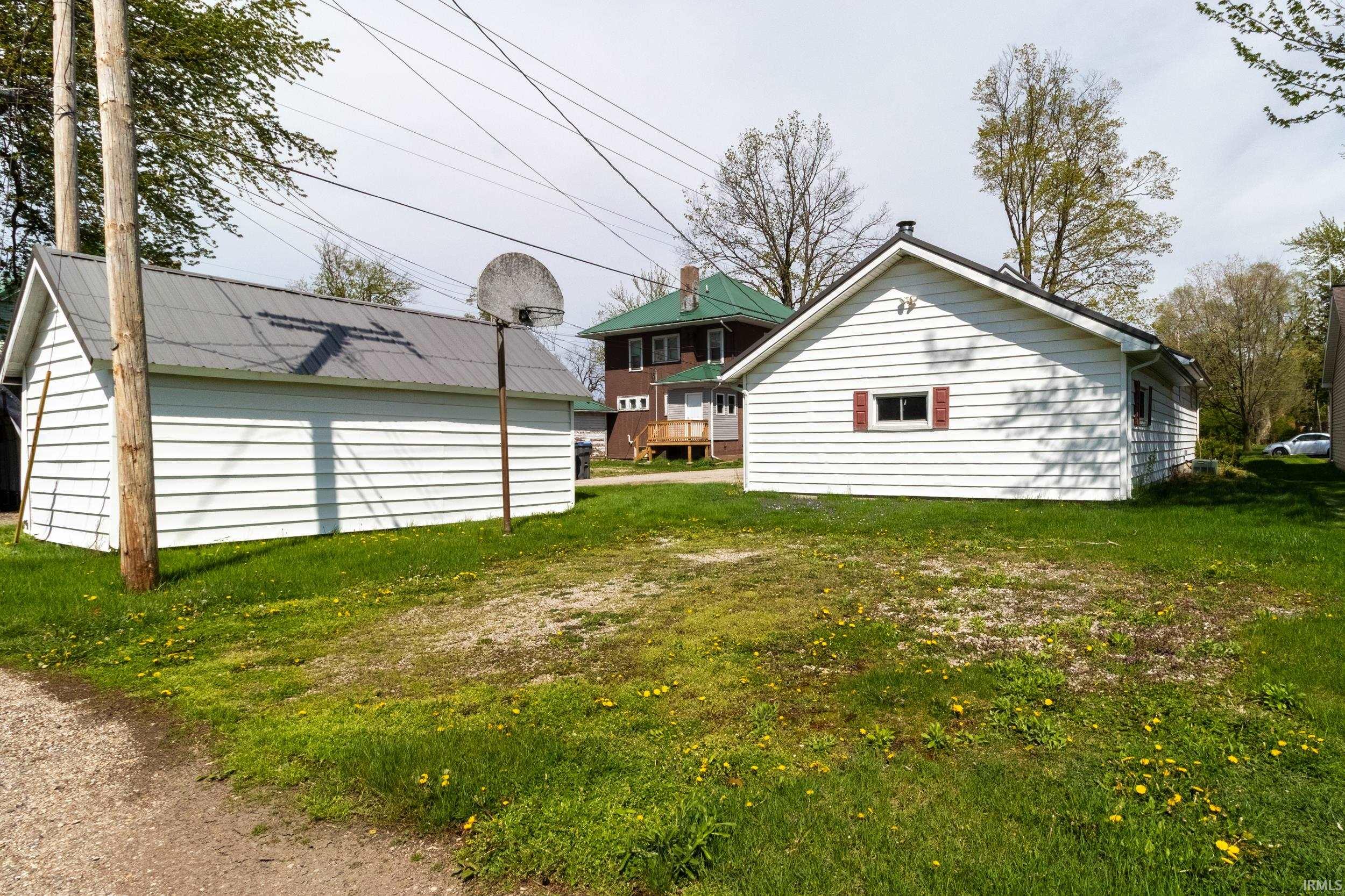 Detached white siding structure featuring a gable roof and red-accented window shutters