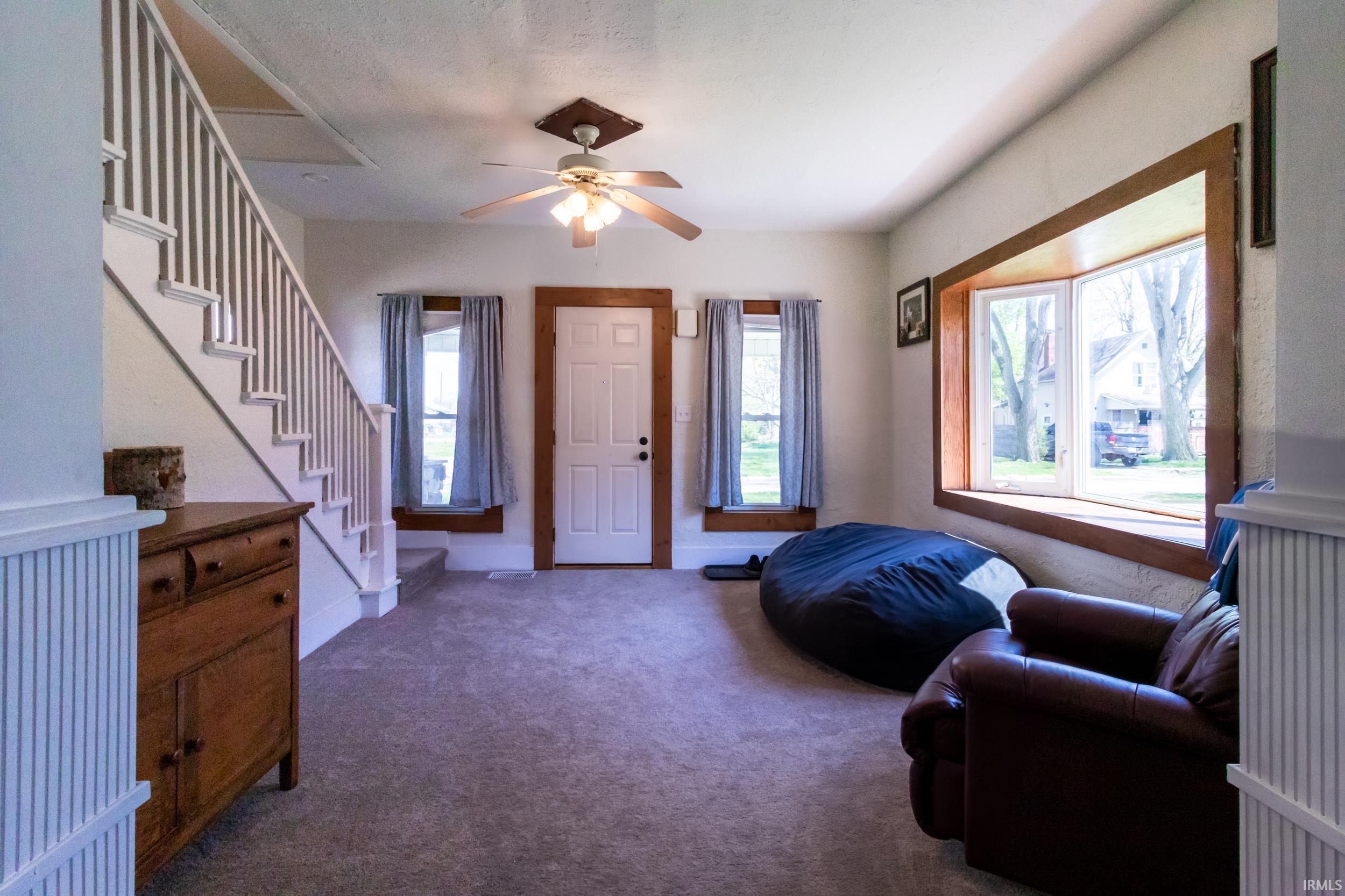 Carpeted living space featuring a prominent staircase with white risers and balusters