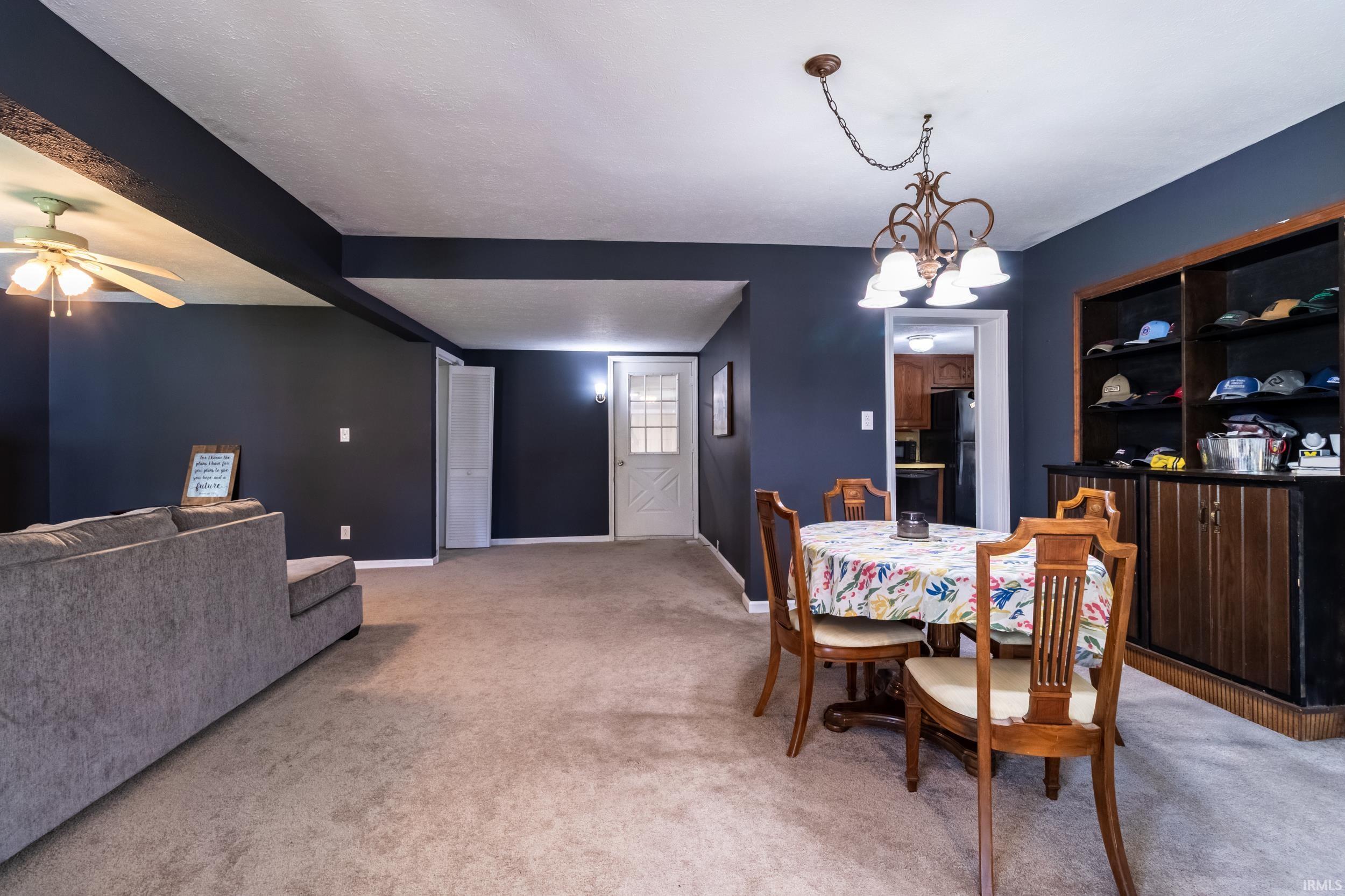 Spacious room featuring neutral carpet flooring, dark accent walls, and a recessed ceiling fan