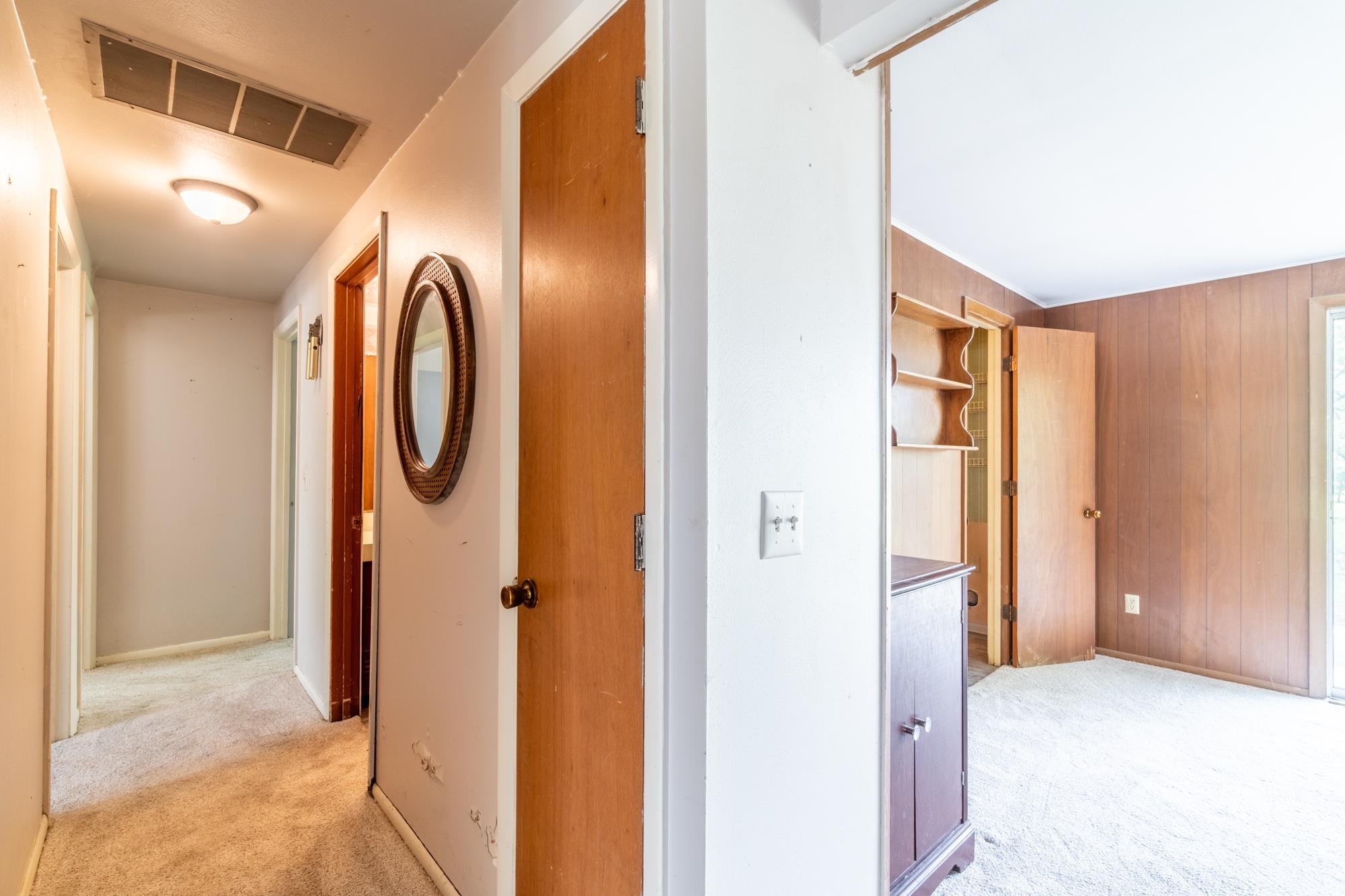 Carpeted hallway with flush-mount lighting, leading to additional rooms
