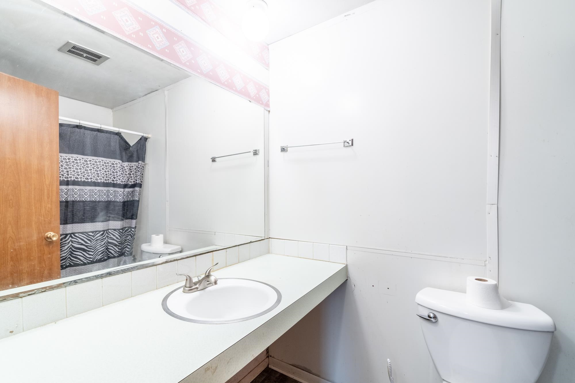Bathroom featuring a built-in vanity with an integrated sink, a brushed nickel faucet, a full-width mirror, and a toilet