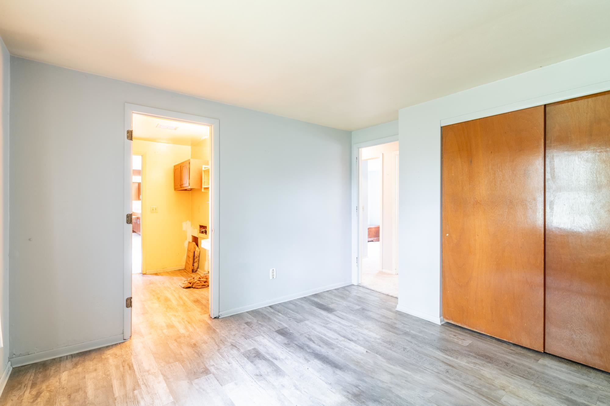 Room featuring light gray walls, wood-finish flooring, and a large bi-fold closet with wood doors