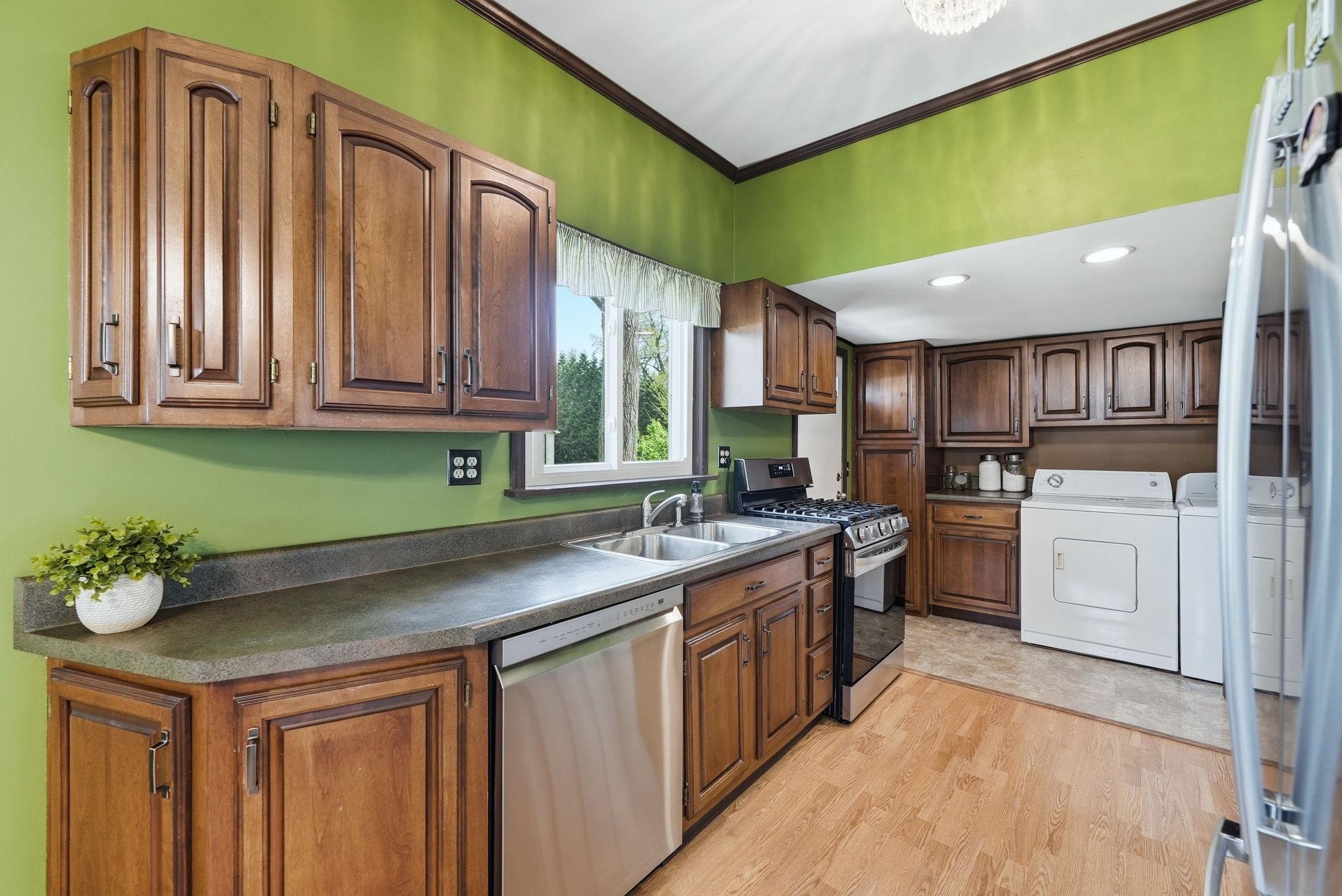 Kitchen featuring wood cabinetry, laminate countertops, a stainless steel dishwasher, and a double basin sink