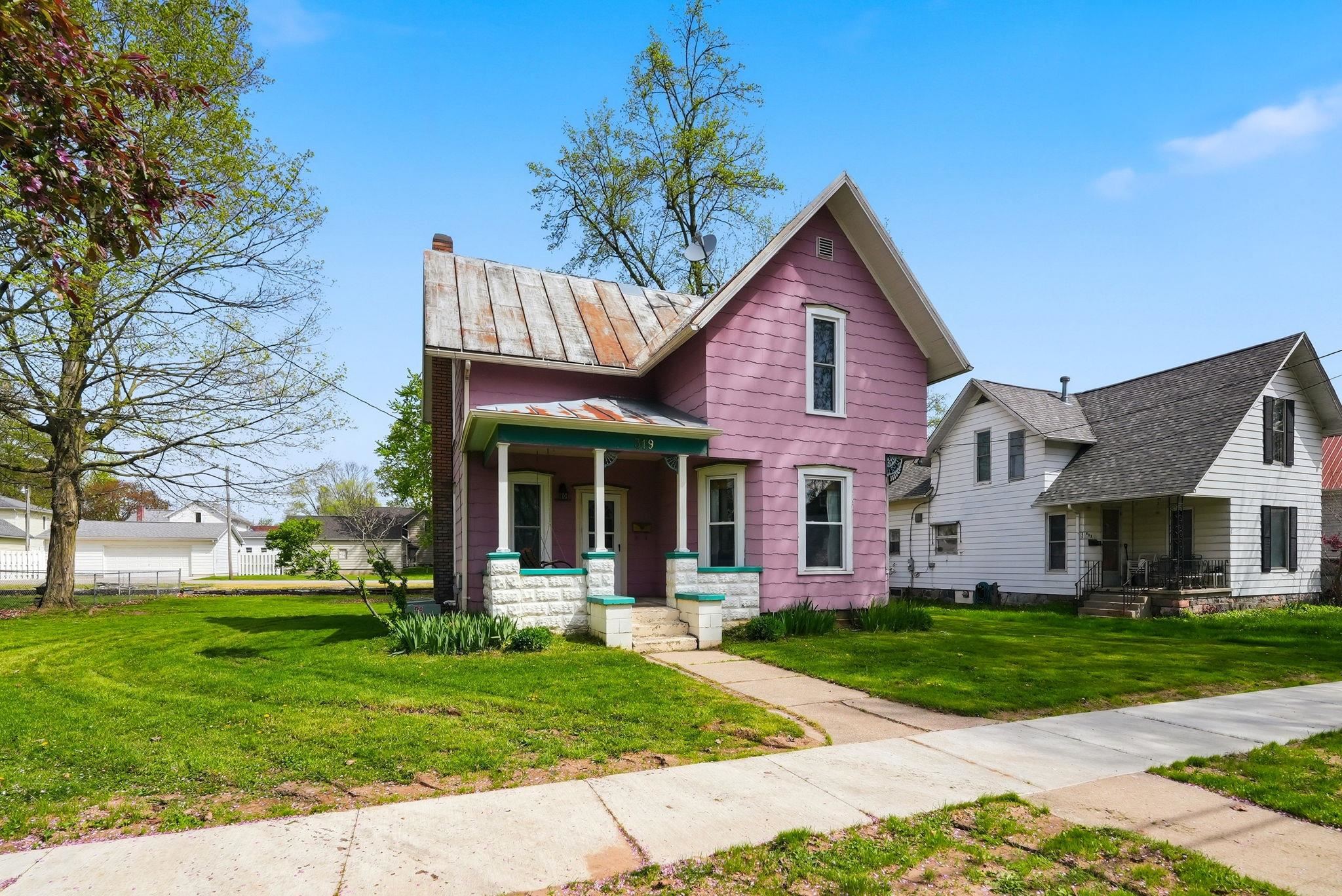 Pink-painted exterior featuring white trim and a covered front porch with stone base pillars