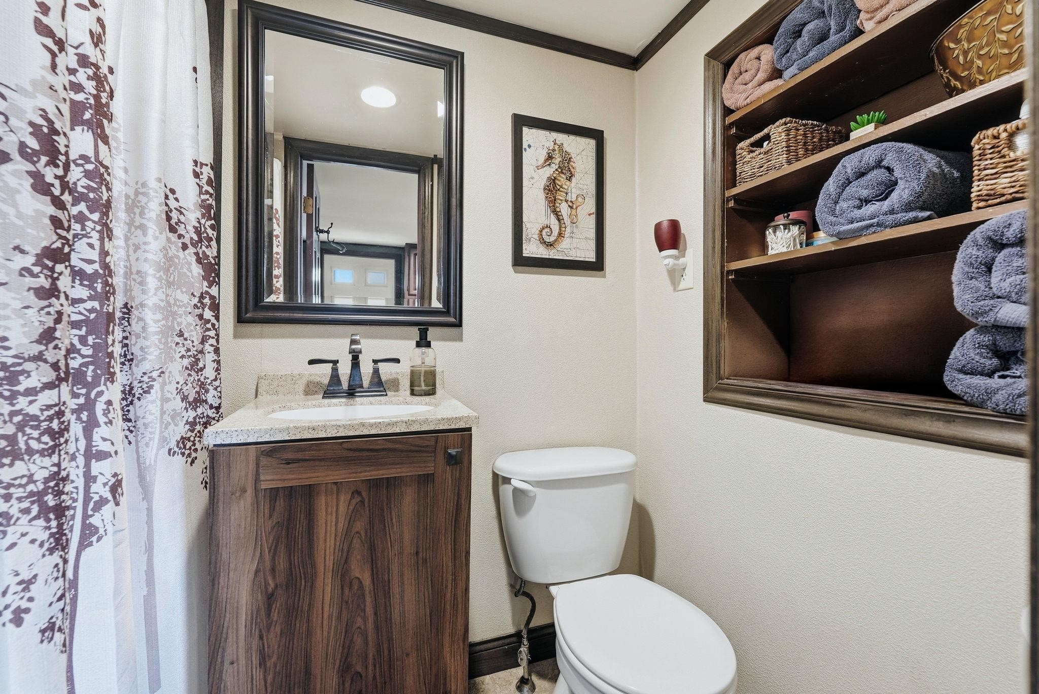 Bathroom featuring a wood-finish vanity with a light-colored countertop and a rectangular undermount sink