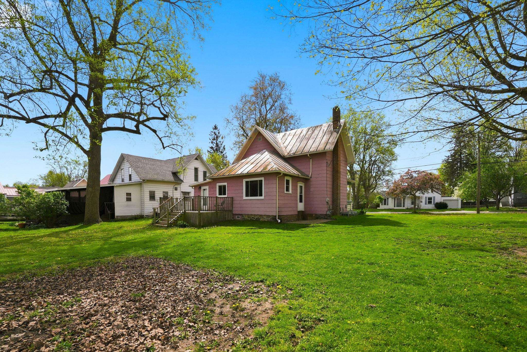Pink-sided residence featuring a metal roof and a stone chimney