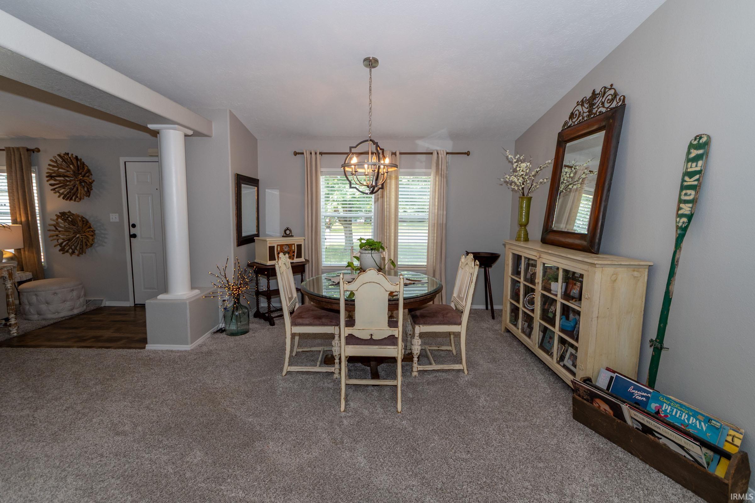 Open-concept dining area featuring a chandelier, a large window with blinds, and light gray wall paint