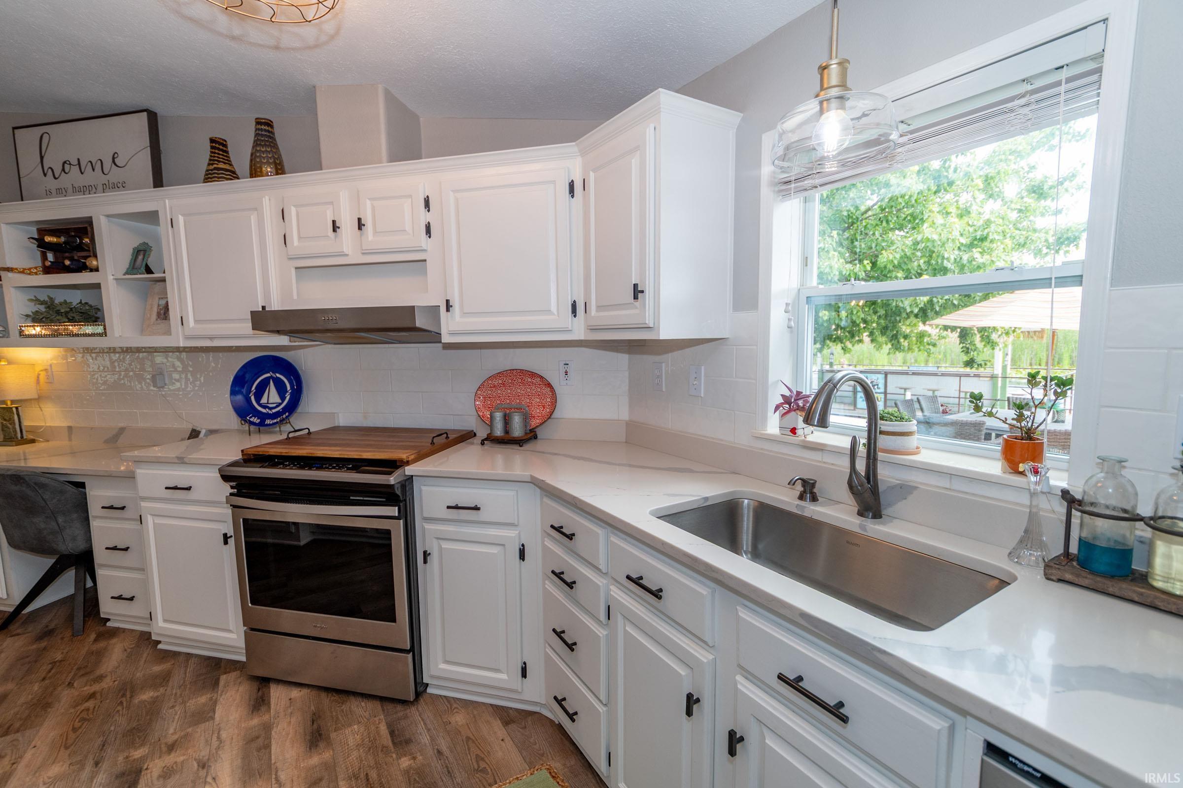 Contemporary kitchen featuring white cabinetry, light-toned countertops, a stainless steel range, and a single-basin sink with a gooseneck faucet