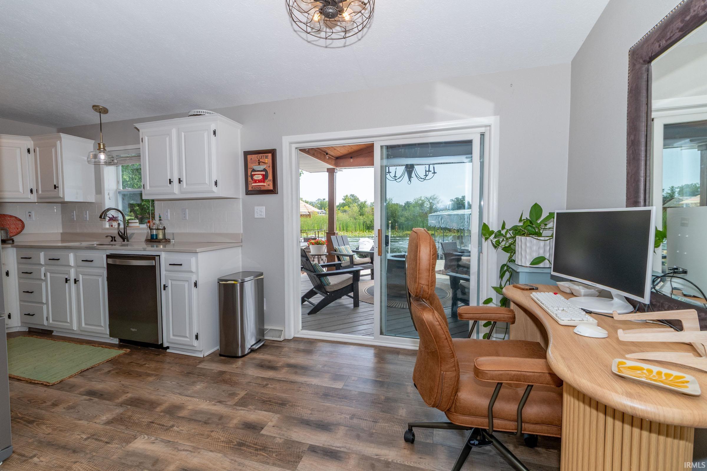 Kitchen and office area featuring wood-finish flooring, white cabinetry with dark hardware, and a stainless steel dishwasher