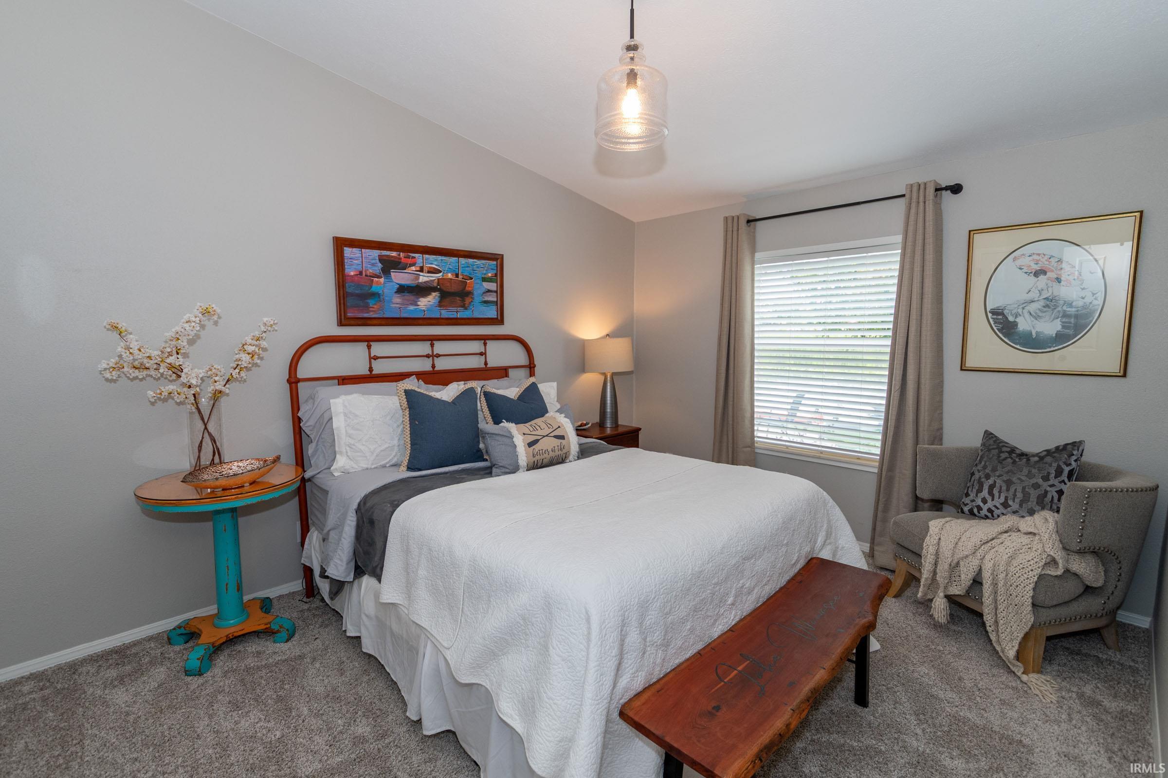 Carpeted room with a vaulted ceiling and a clear glass pendant light