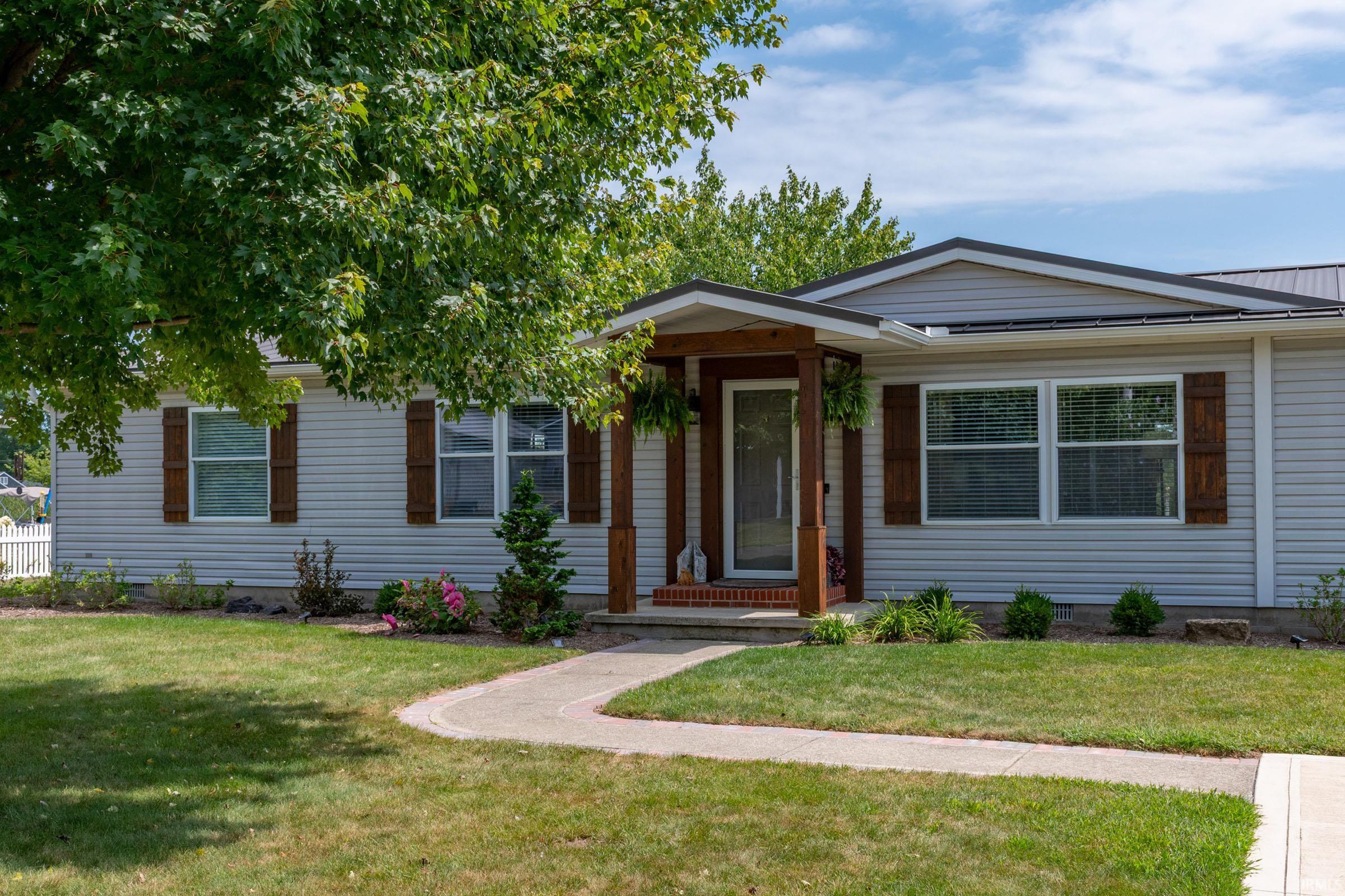 Exterior featuring light-colored siding, dark metal roofing, and a covered porch entry