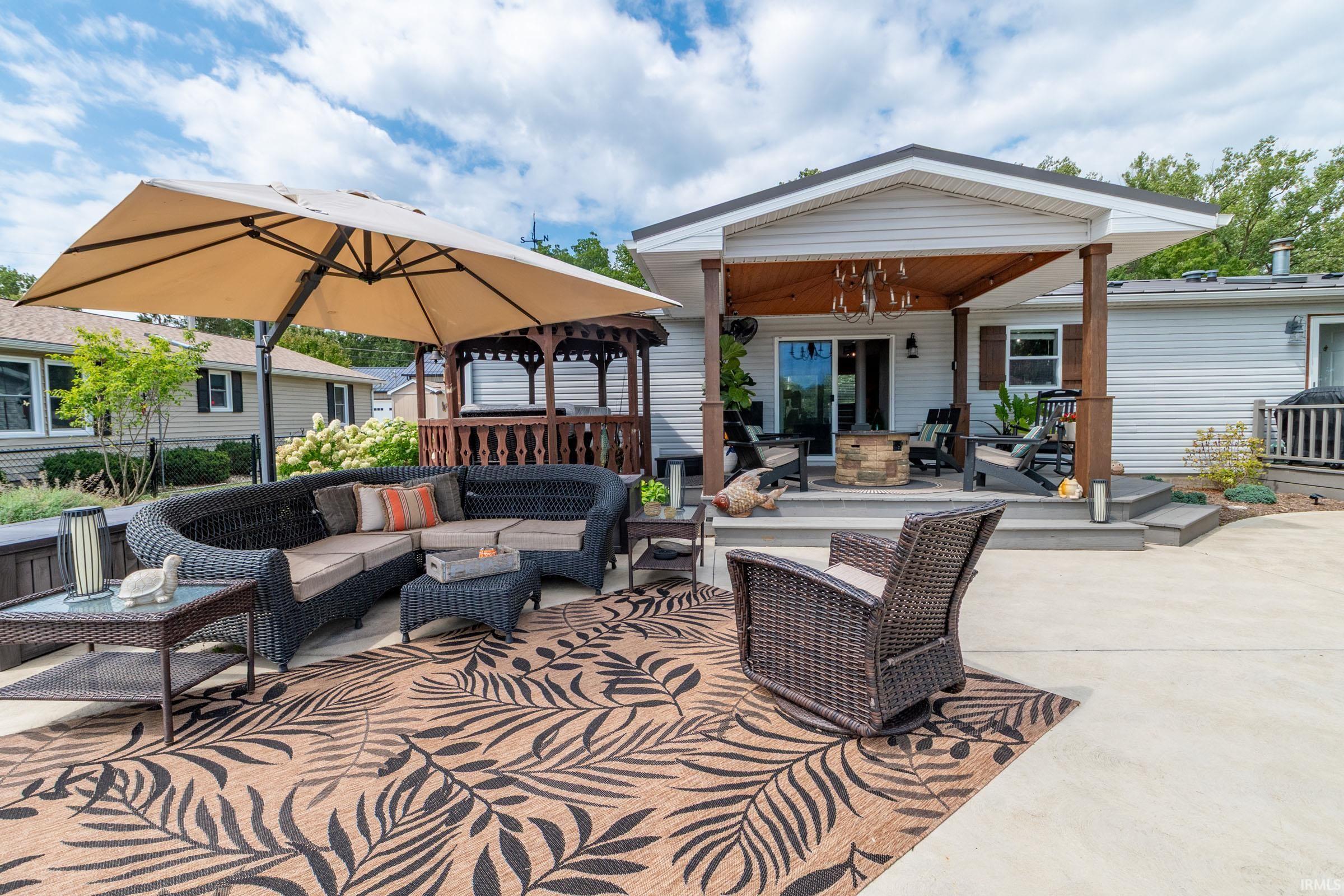 Expansive concrete patio area featuring a covered porch, multi-level composite decking, and a built-in gazebo