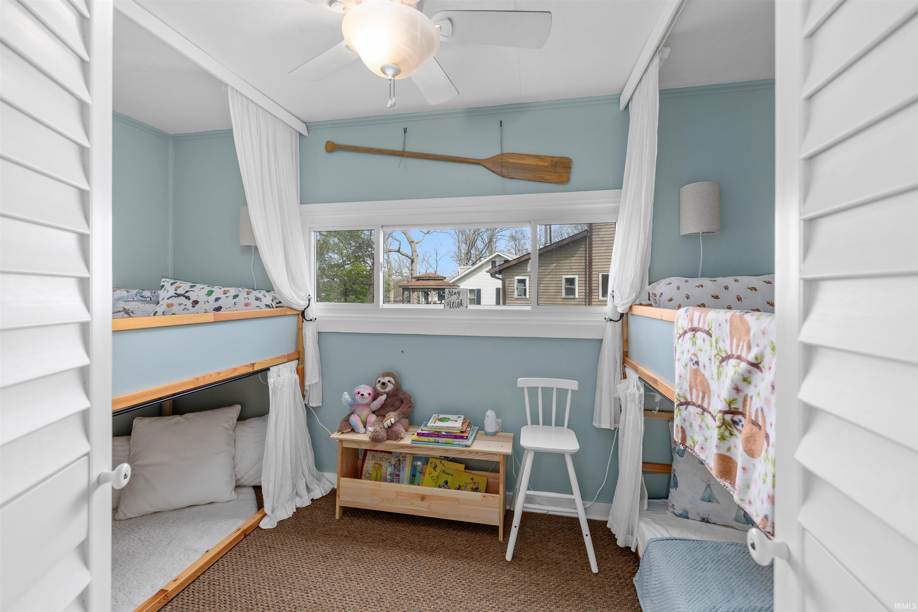 Built-in bunk beds with privacy curtains define this room, featuring light blue walls and a window with white trim