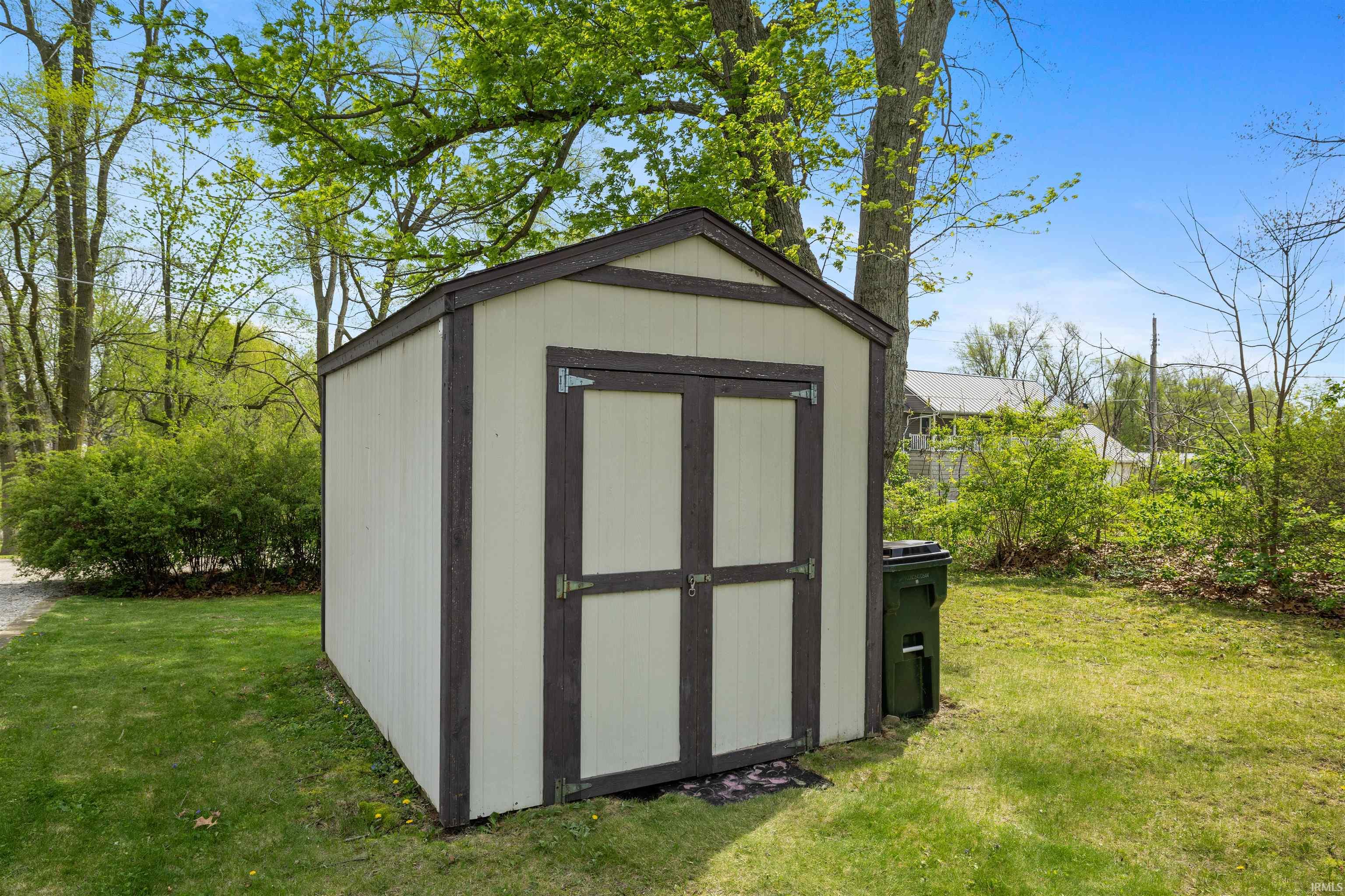 Exterior storage shed featuring vertical panel siding and a gabled roofline