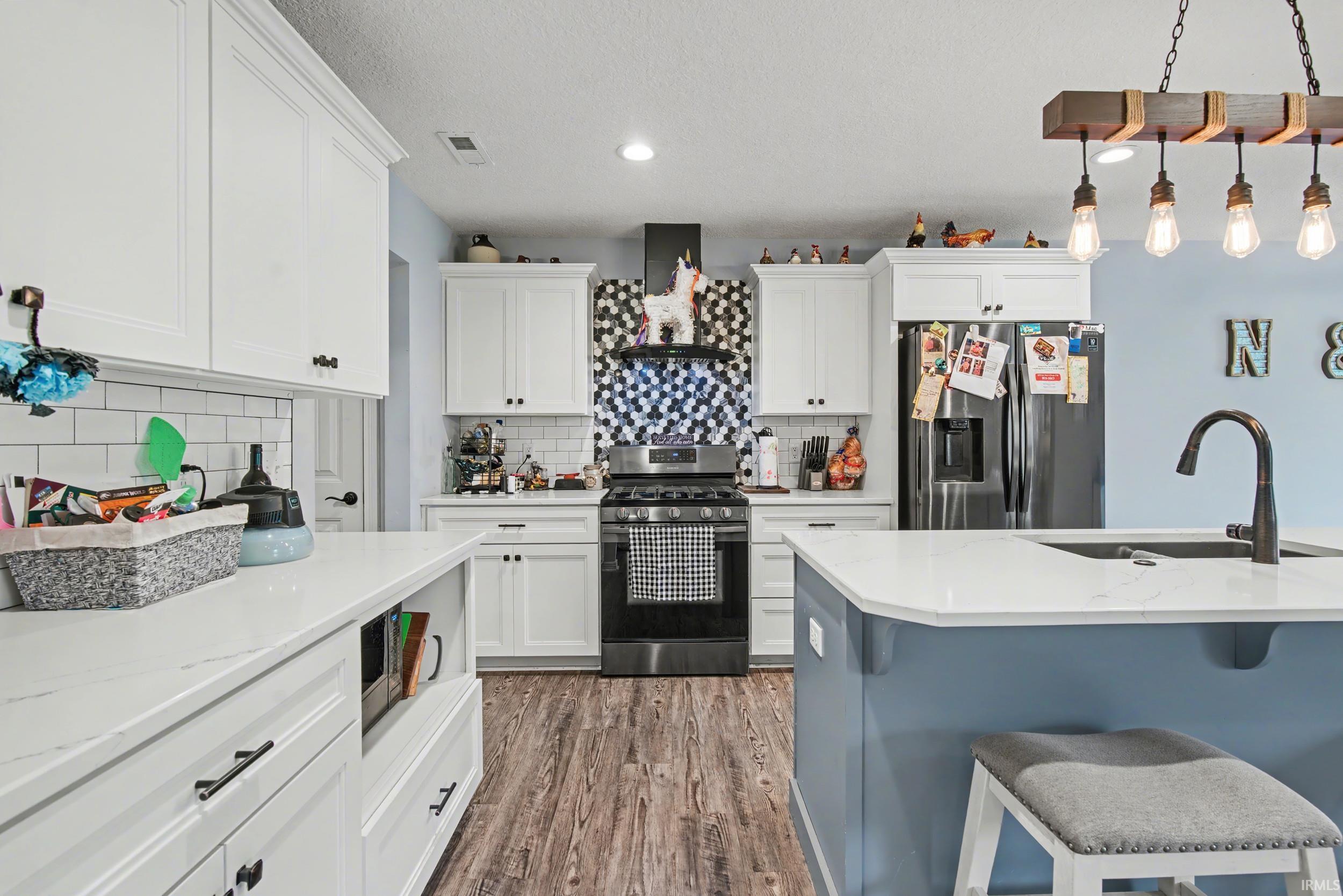 Contemporary kitchen featuring white cabinetry, quartz countertops, wood-finish flooring, a stainless steel gas range with a tile backsplash, and a black gooseneck faucet