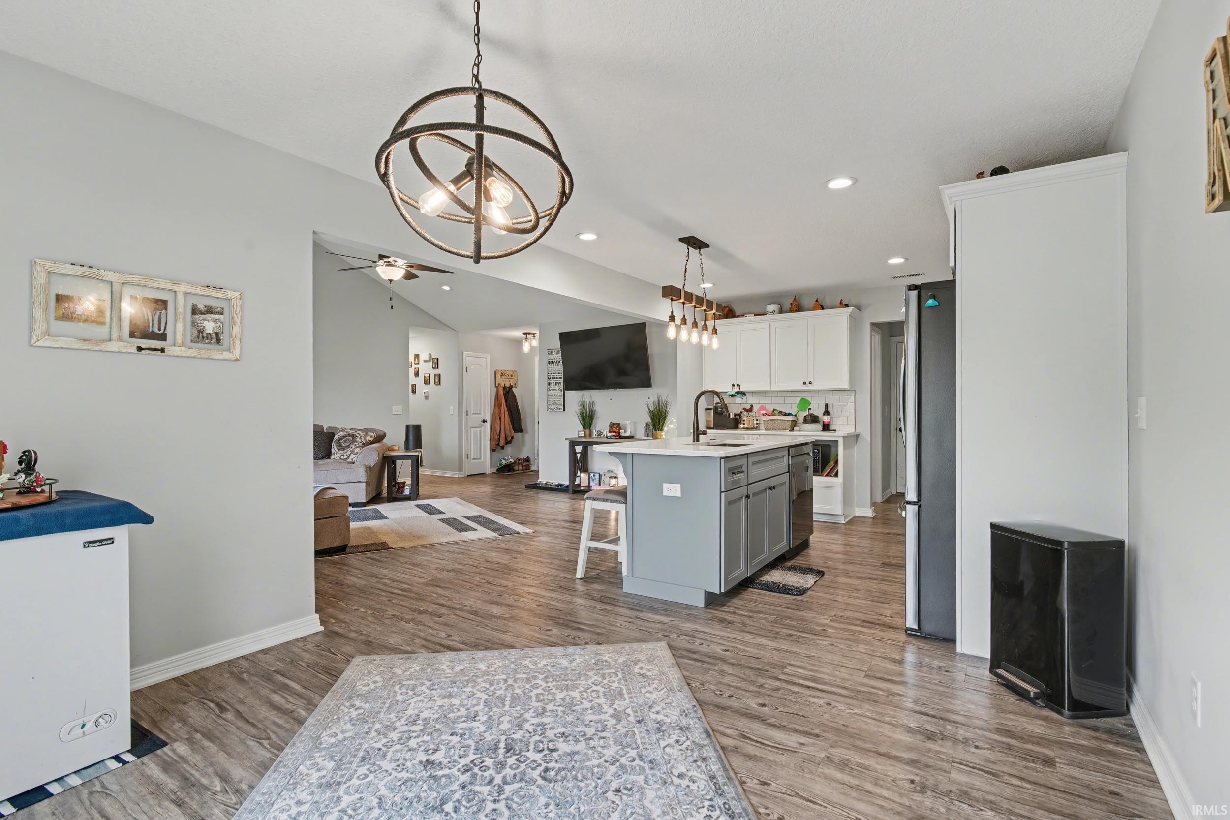 Open-concept living space featuring wood-finish flooring, recessed lighting, and a vaulted ceiling