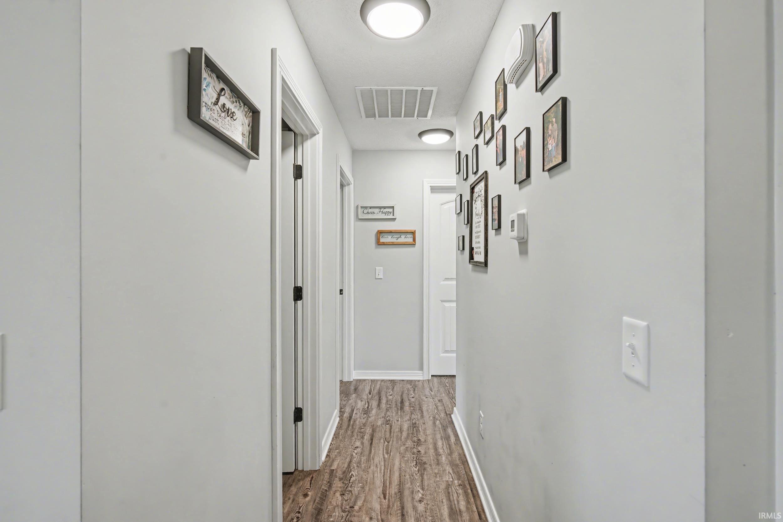 Hallway featuring wood-finish flooring, light gray wall paint, white trim, and flush-mount ceiling lighting