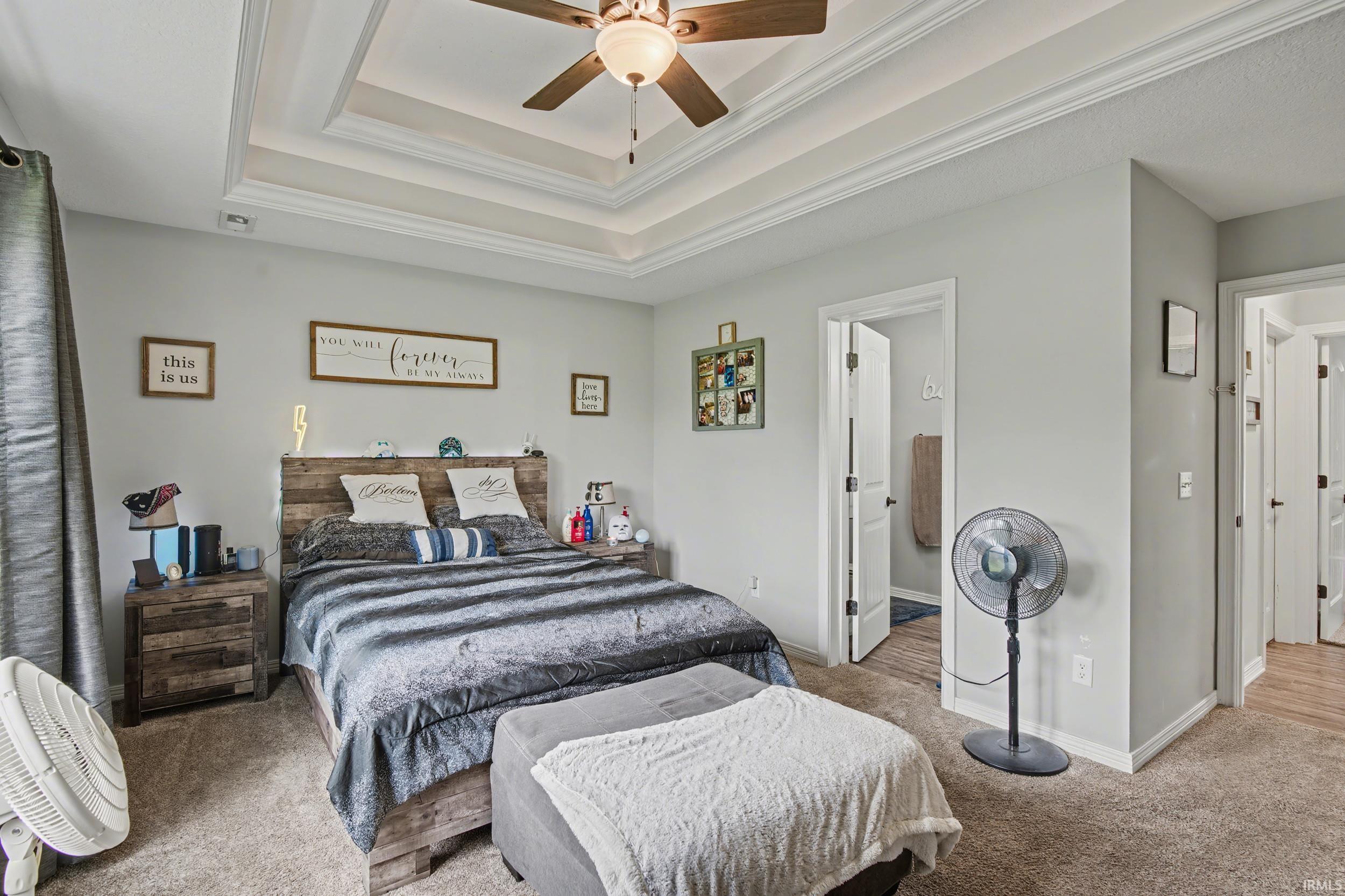 Bedroom featuring a multi-tiered tray ceiling with crown molding and ceiling fan