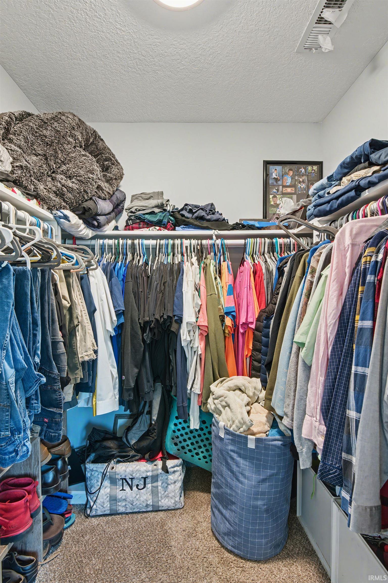 Walk-in closet featuring extensive built-in shelving and hanging rods