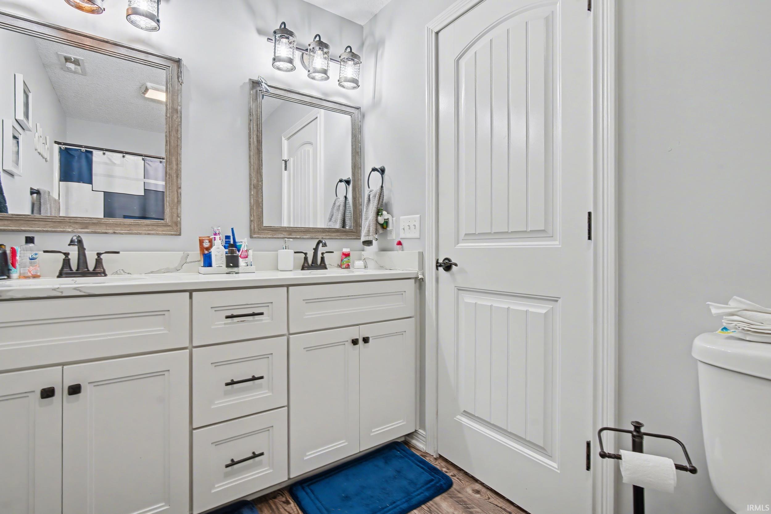 Double vanity with white cabinetry and dark hardware, featuring dual mirrors with distressed wood-finish frames, and a white countertop