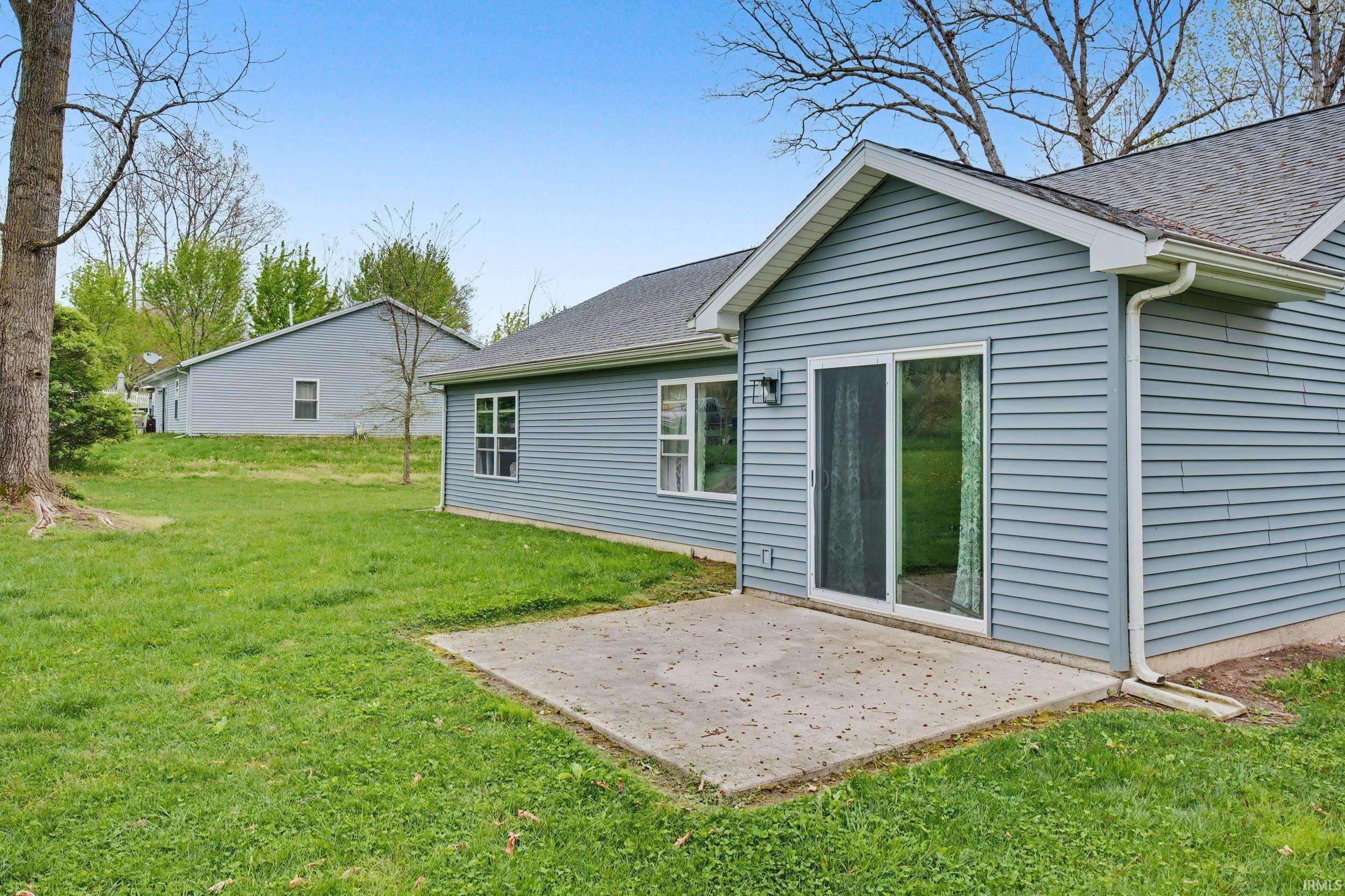 Rear exterior featuring light blue horizontal siding, a gabled roofline, and a concrete patio