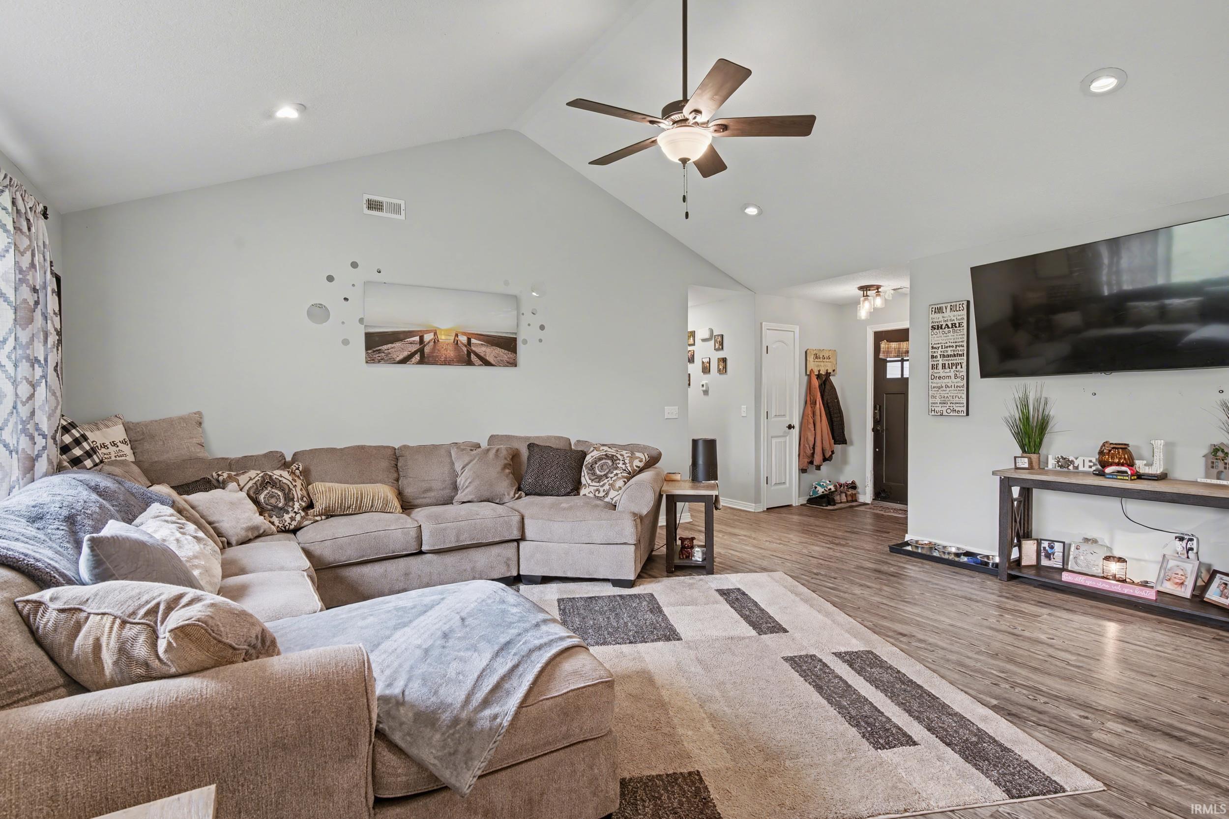 Spacious living area featuring a vaulted ceiling with a ceiling fan, recessed lighting, and wood-finish flooring