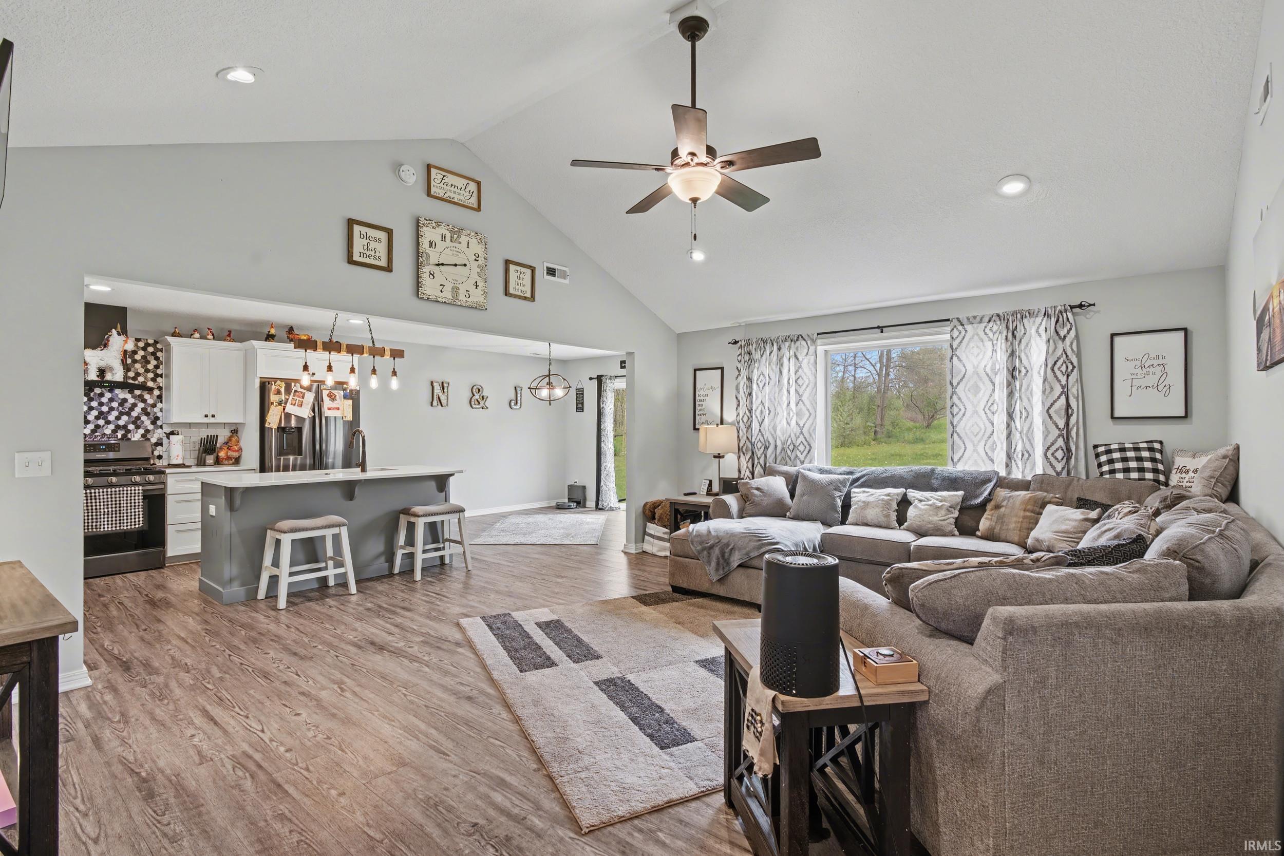 Vaulted ceiling living area featuring wood-finish flooring, recessed lighting, and a ceiling fan