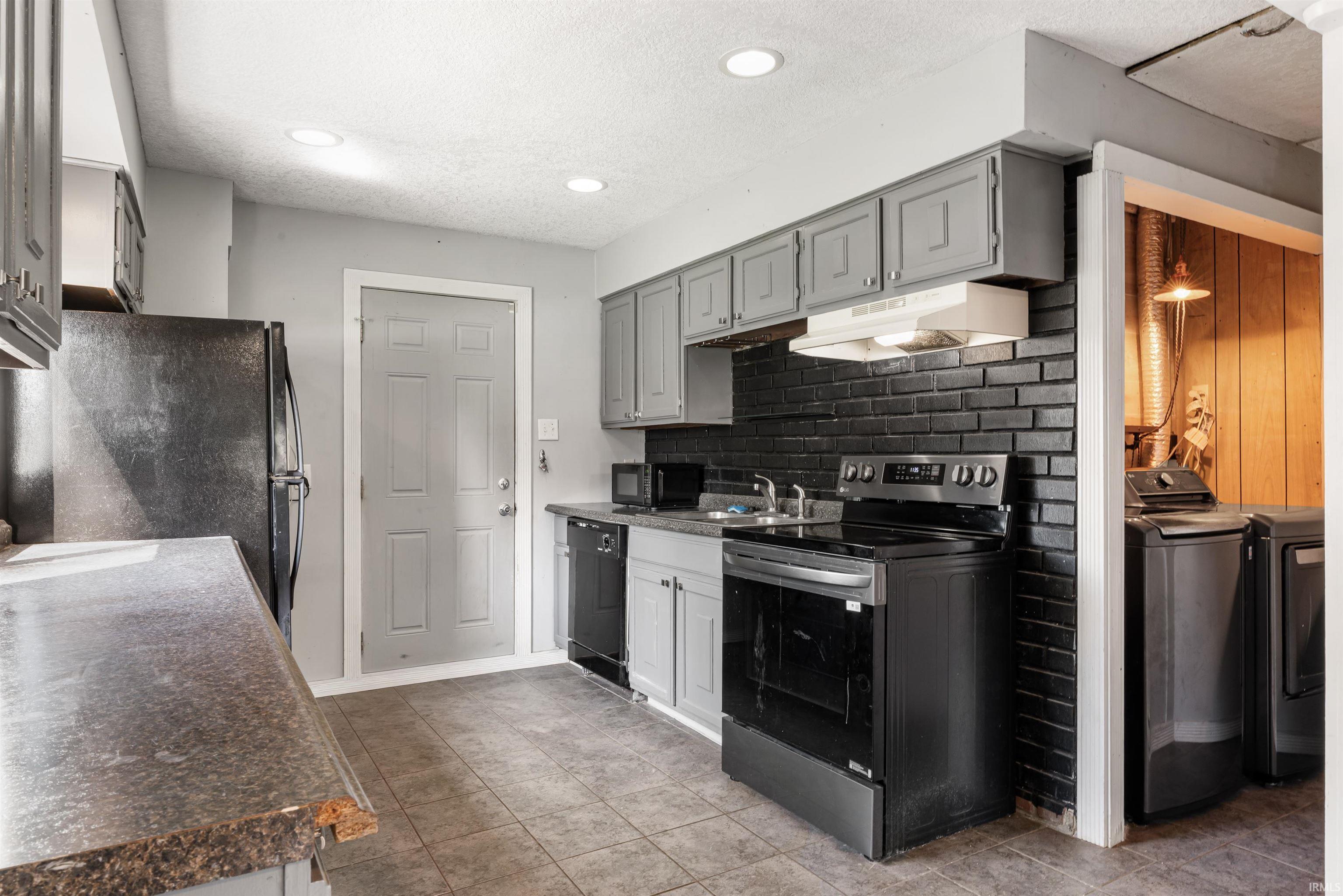 Kitchen featuring dark gray cabinetry, laminate countertops, a black brick-style backsplash, and recessed lighting
