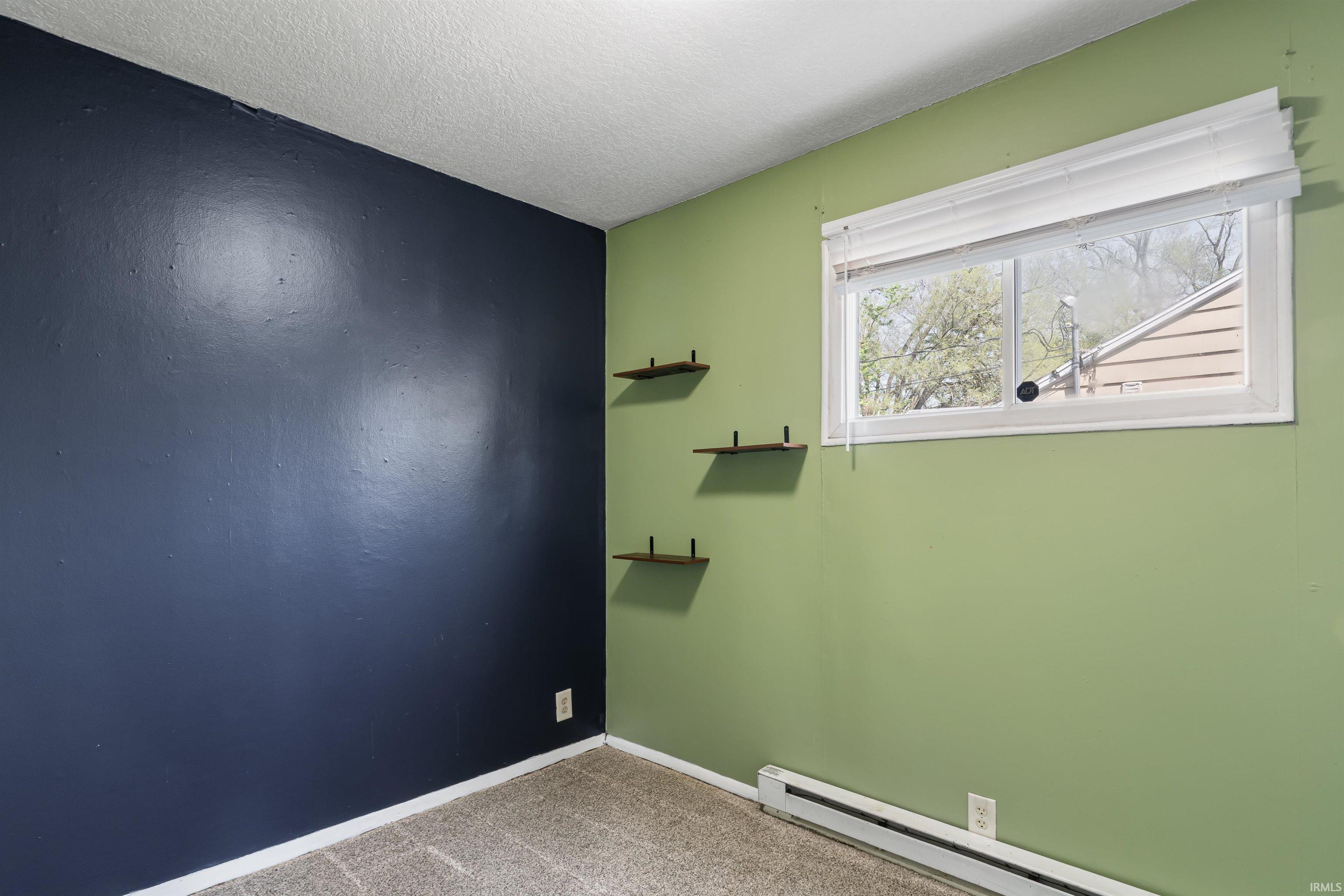 Room featuring two-tone wall paint, a window with white blinds, and three wall-mounted shelves