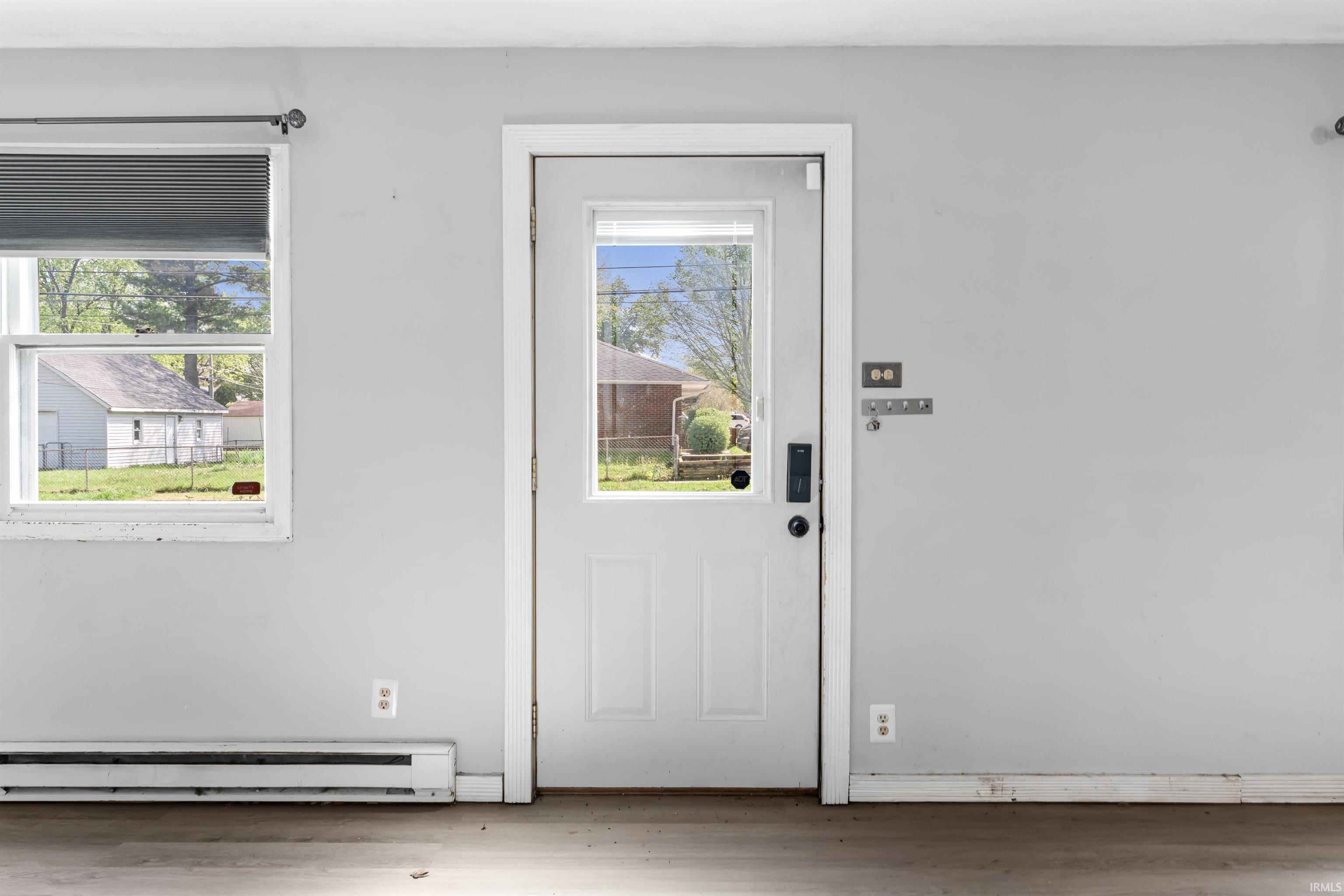 White paneled door with a half-light window, complemented by a large window with privacy blinds