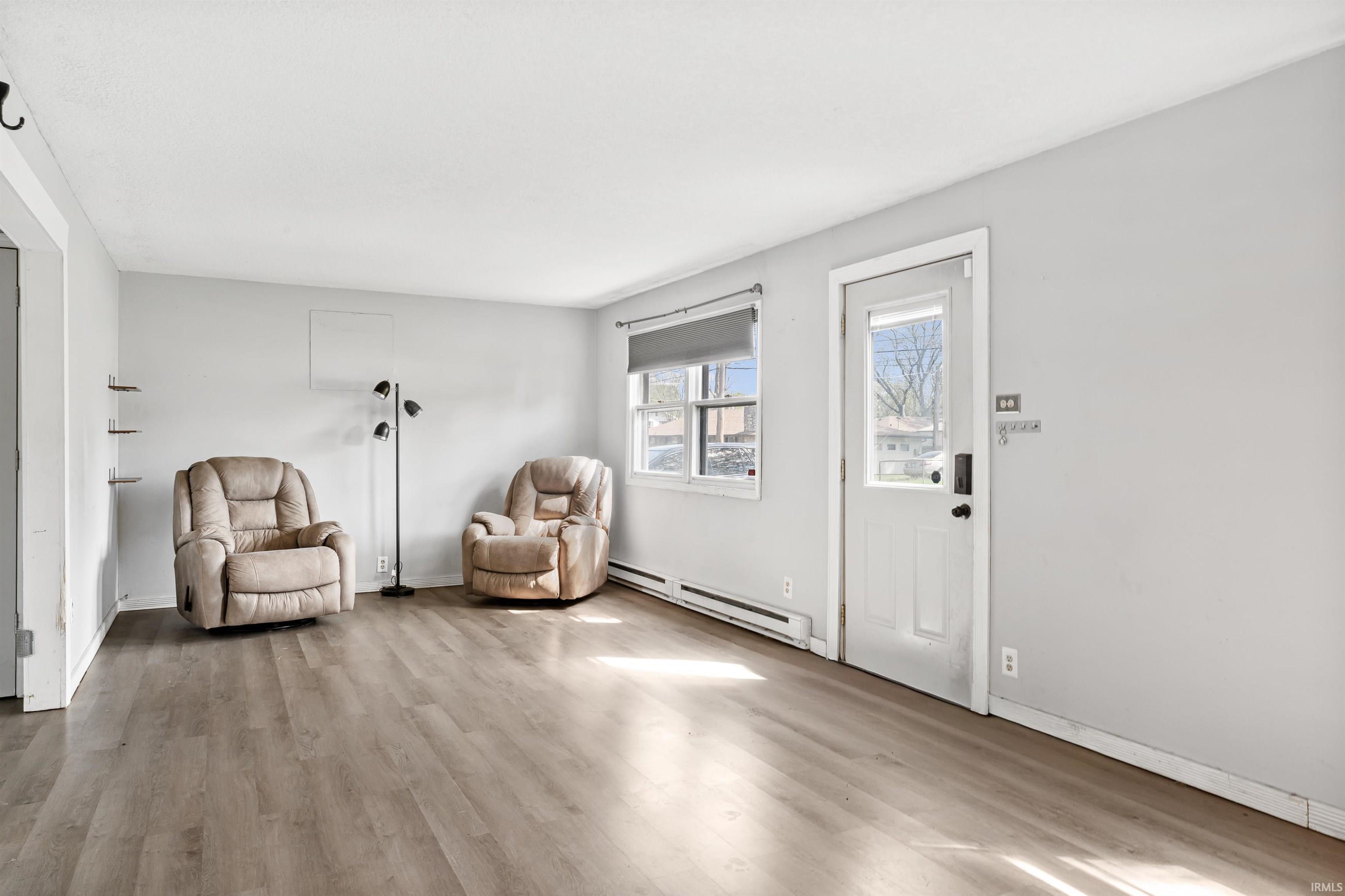Spacious room featuring wood-finish flooring, light grey walls, and white trim