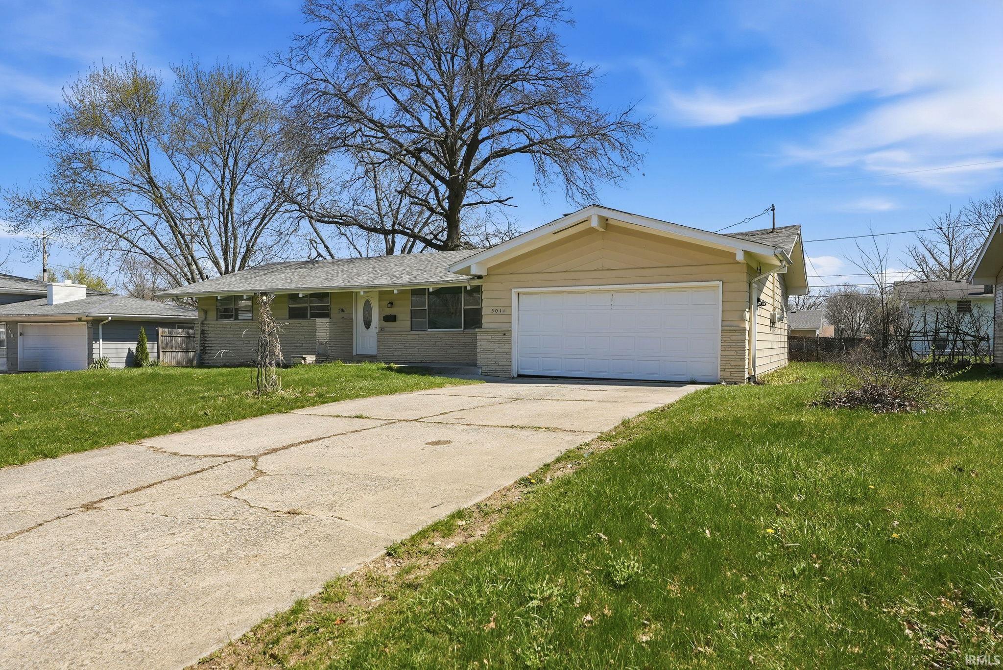 Ranch-style residence featuring a prominent attached two-car garage with a white door