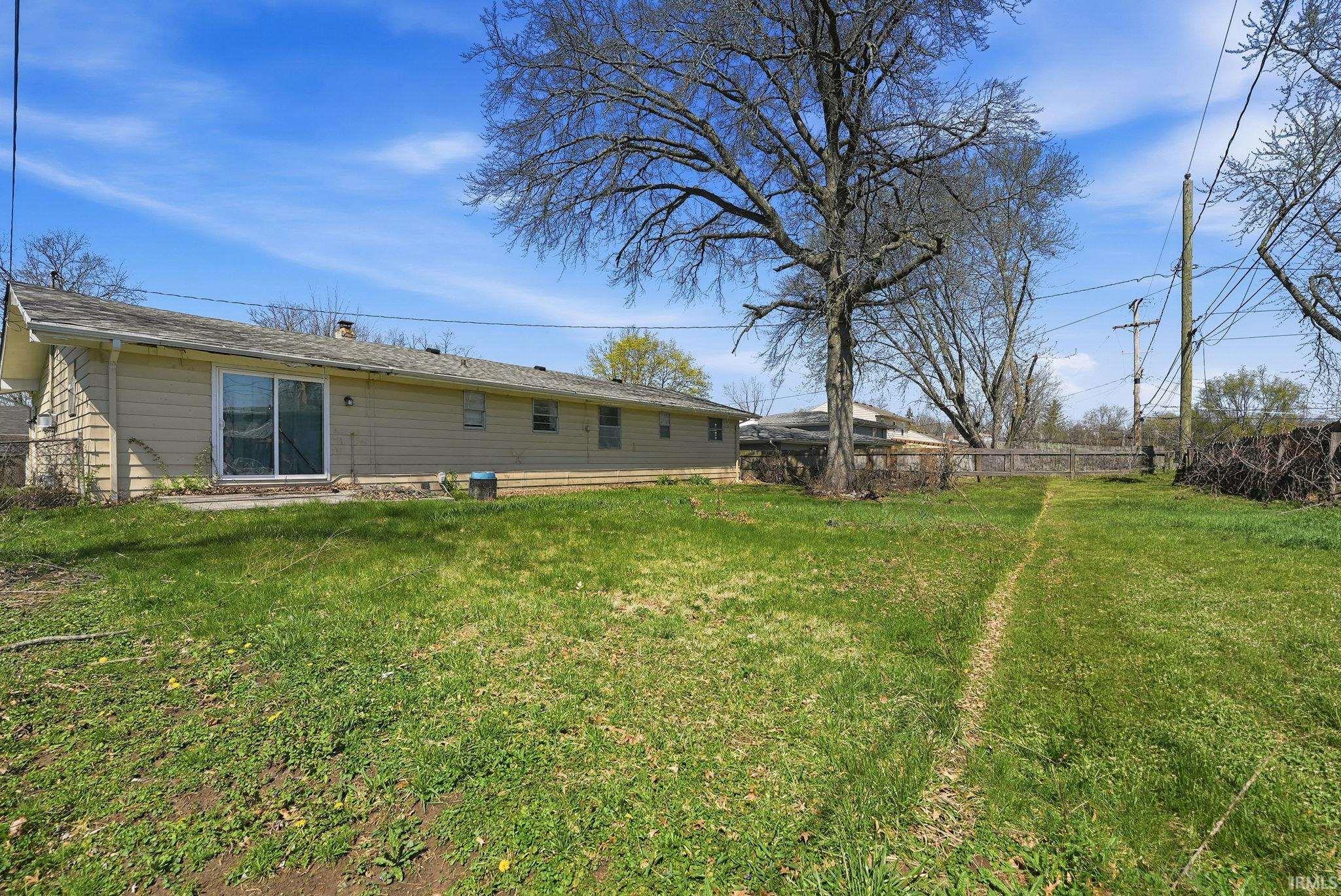 Expansive rear yard featuring mature trees and a wood fence
