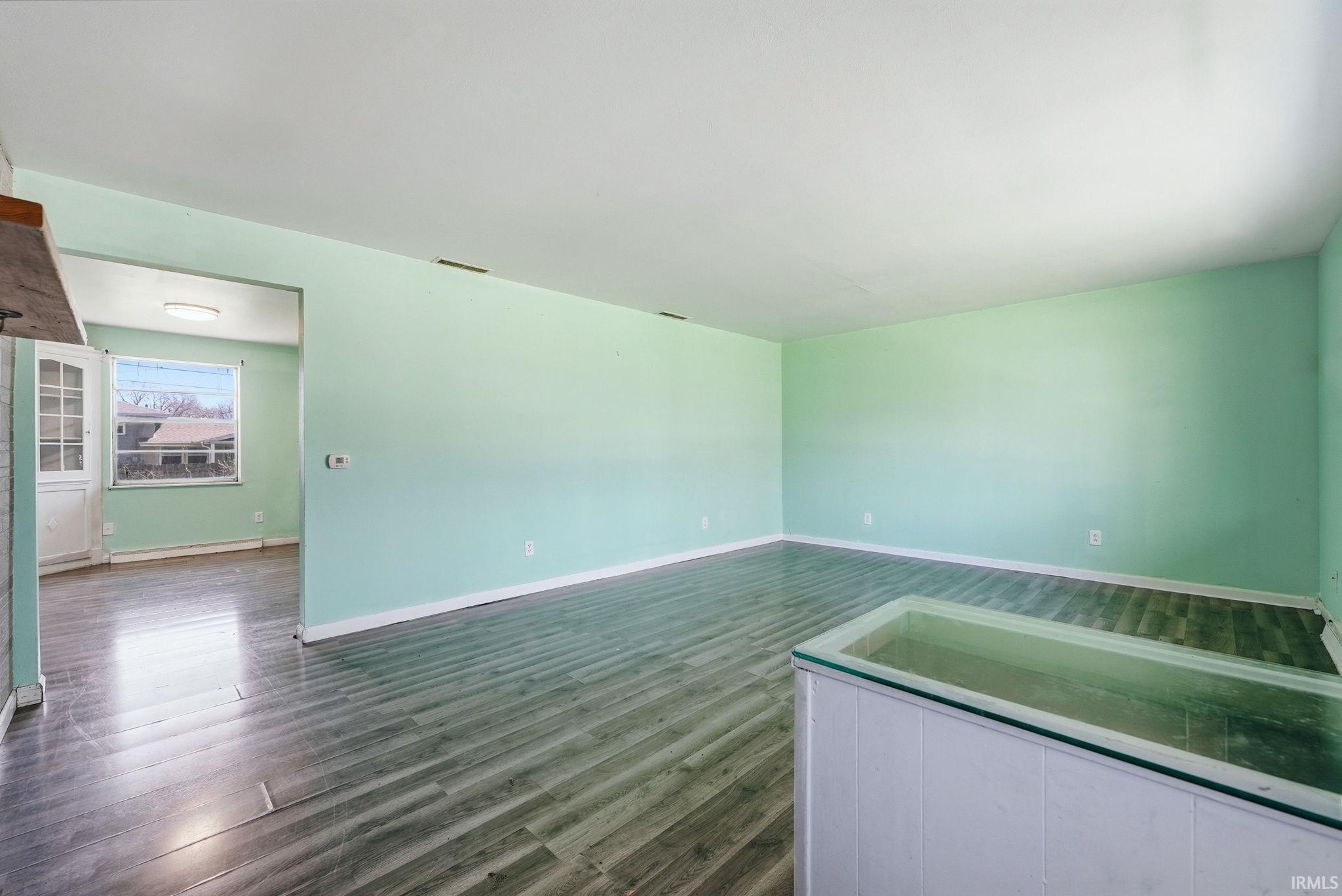 Spacious interior featuring wood-finish flooring, a pass-through window, and light green walls