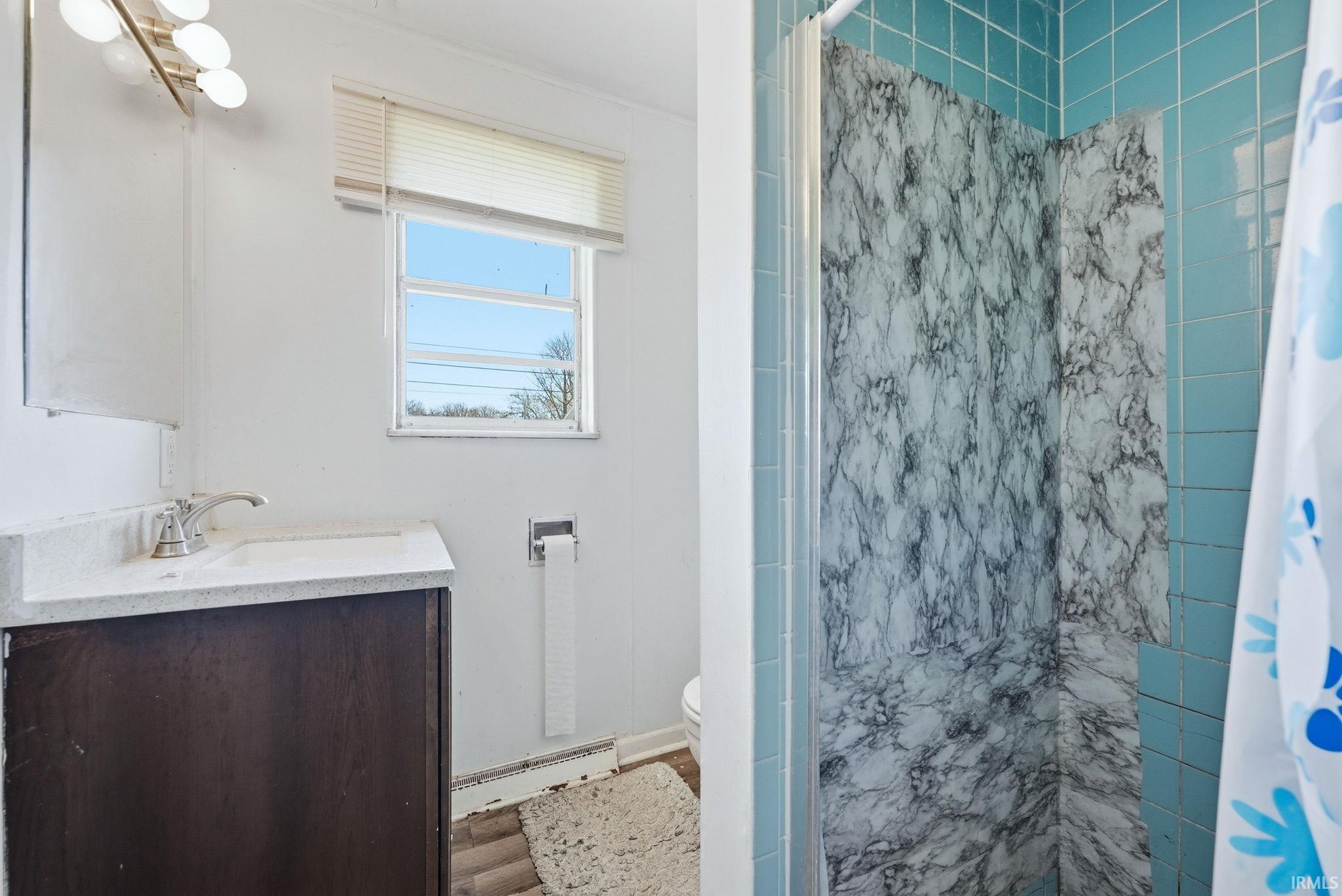 Bathroom featuring a dark wood-finish vanity with a light countertop, a single basin sink, and a chrome faucet