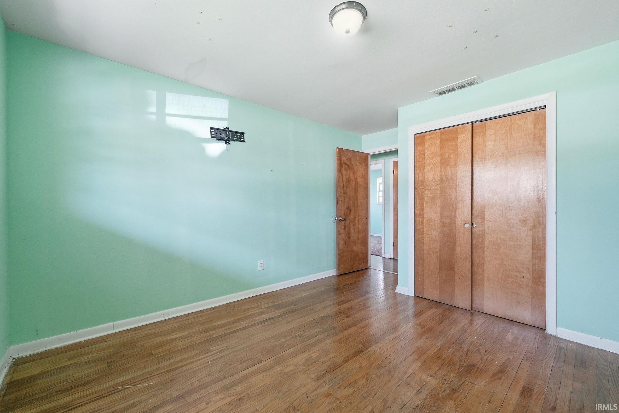 Wood-finish flooring throughout, featuring a bi-fold closet with wood doors