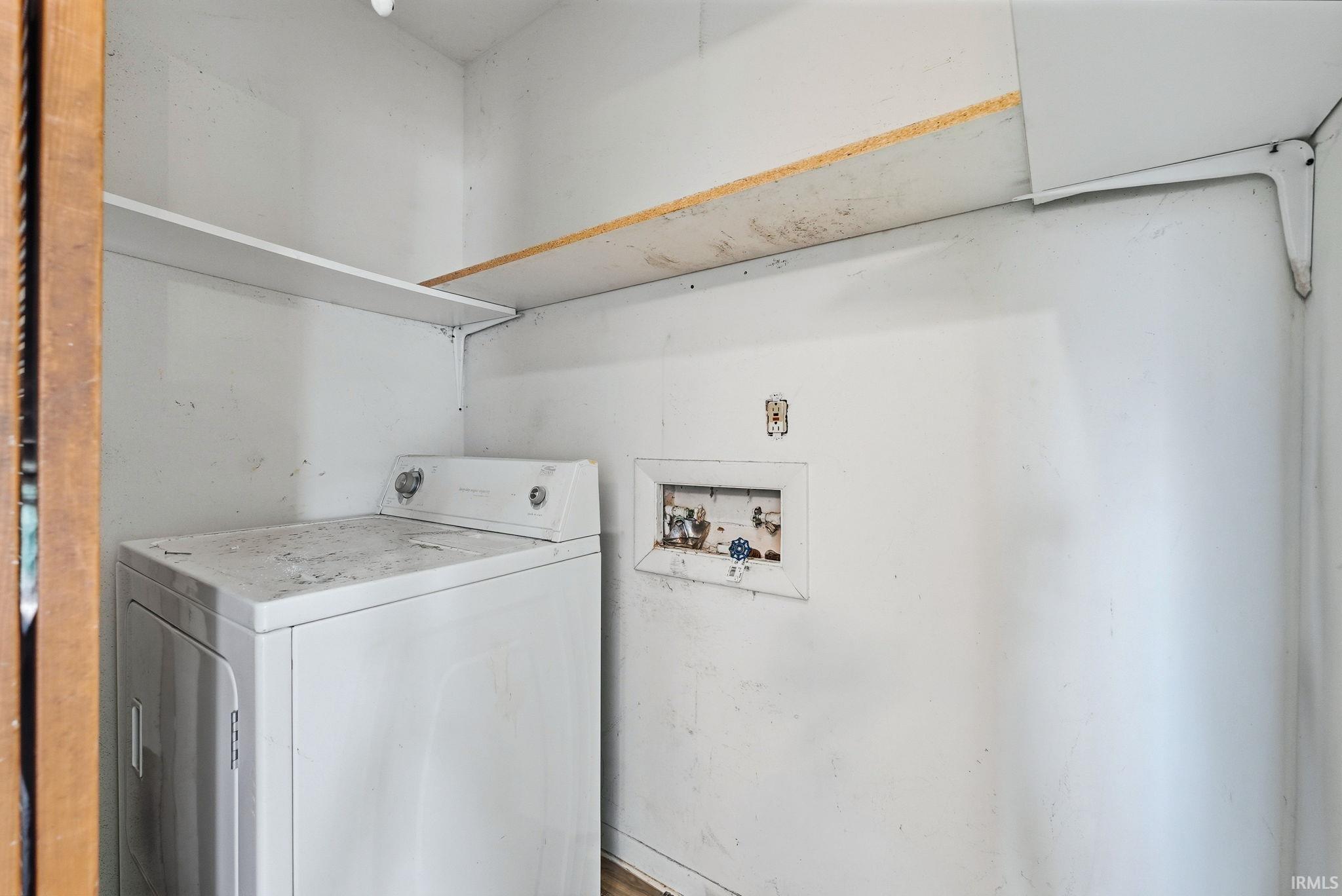 Laundry area with white walls and overhead shelving