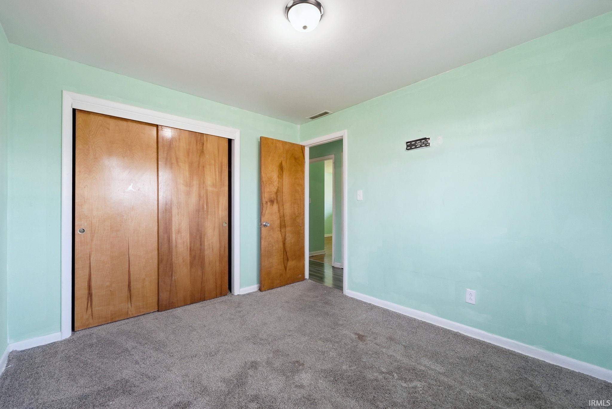 Room featuring light green walls, grey carpeting, and white baseboards